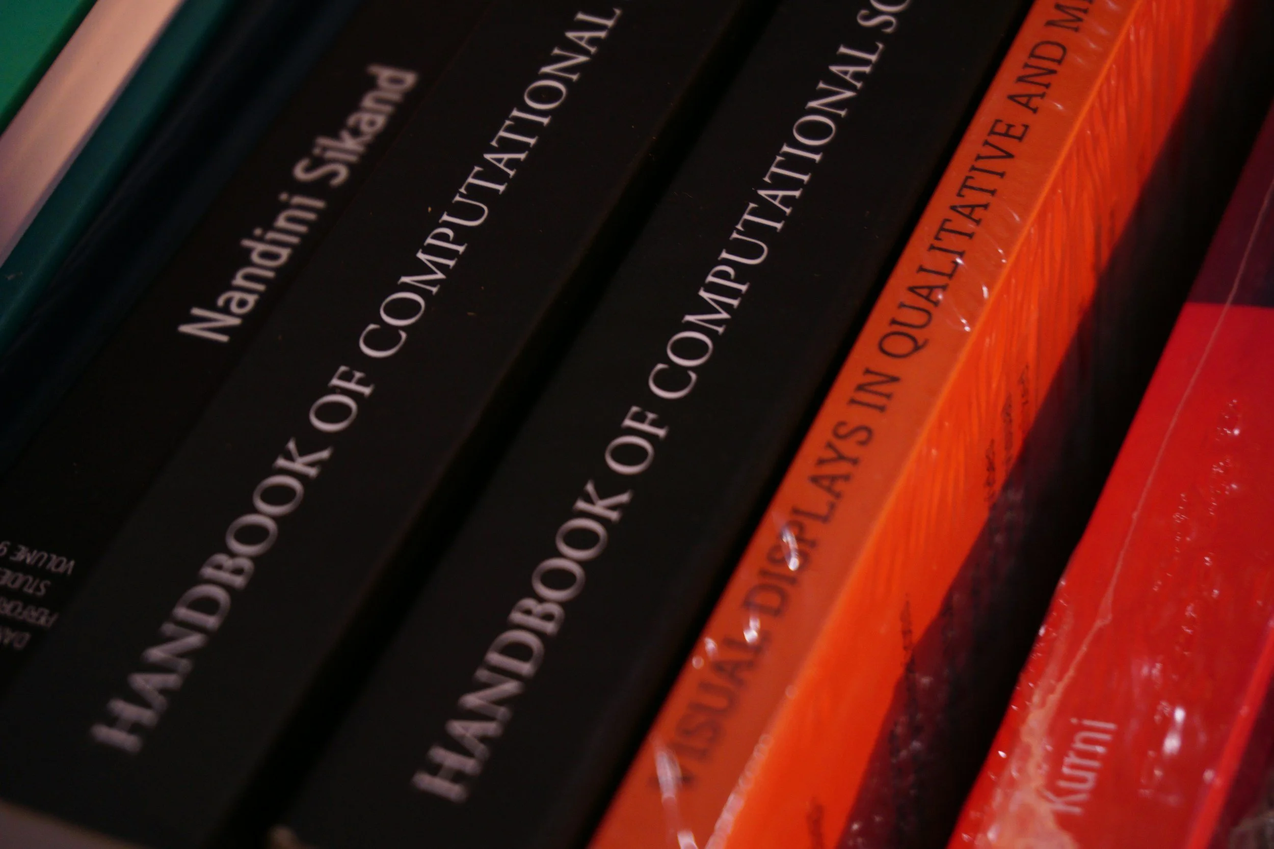 Close-up of research book binders, including three black and two red volumes used as computational references.