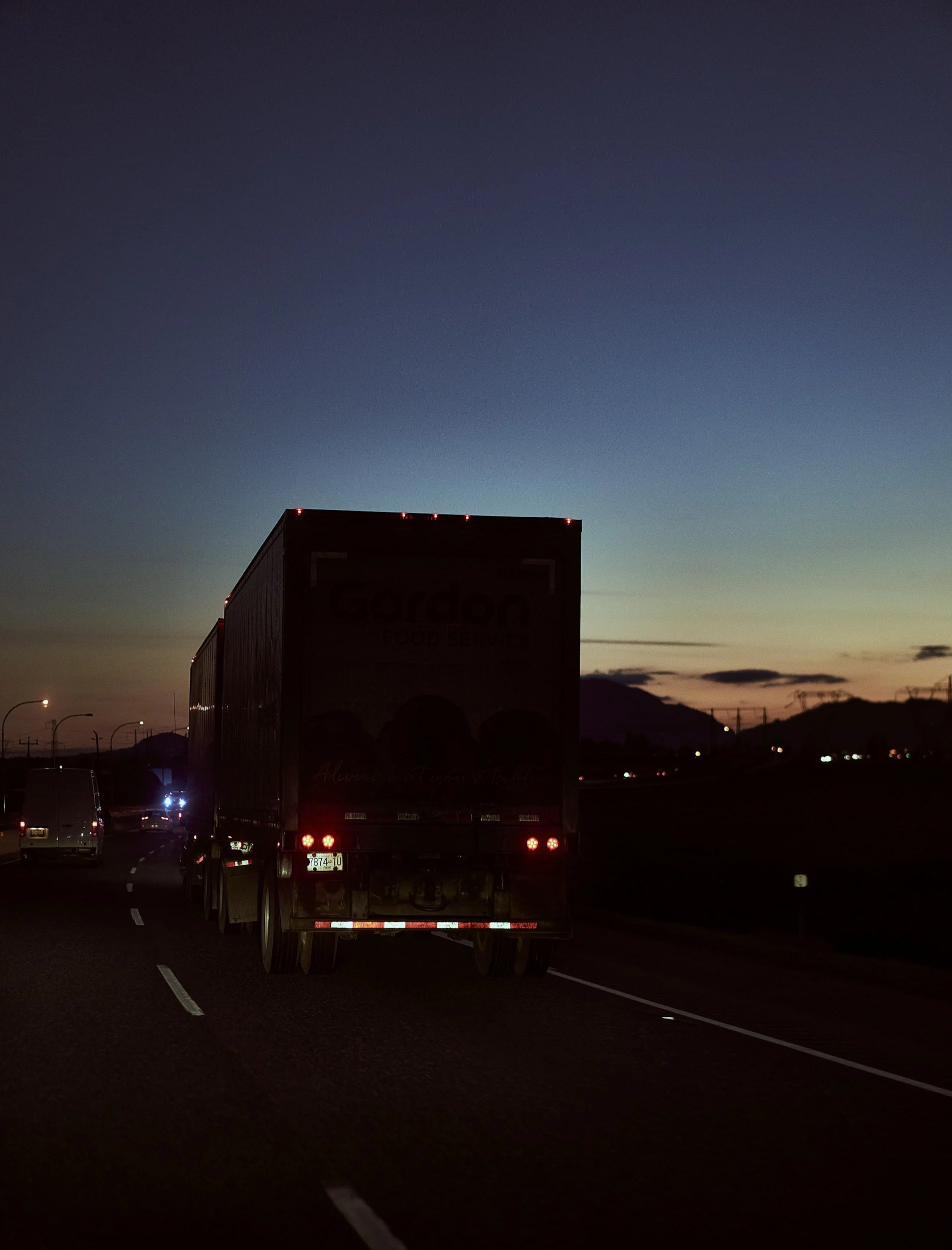 Damaged blue semi-truck with front end crash in a parking lot with other buses and trucks in the background