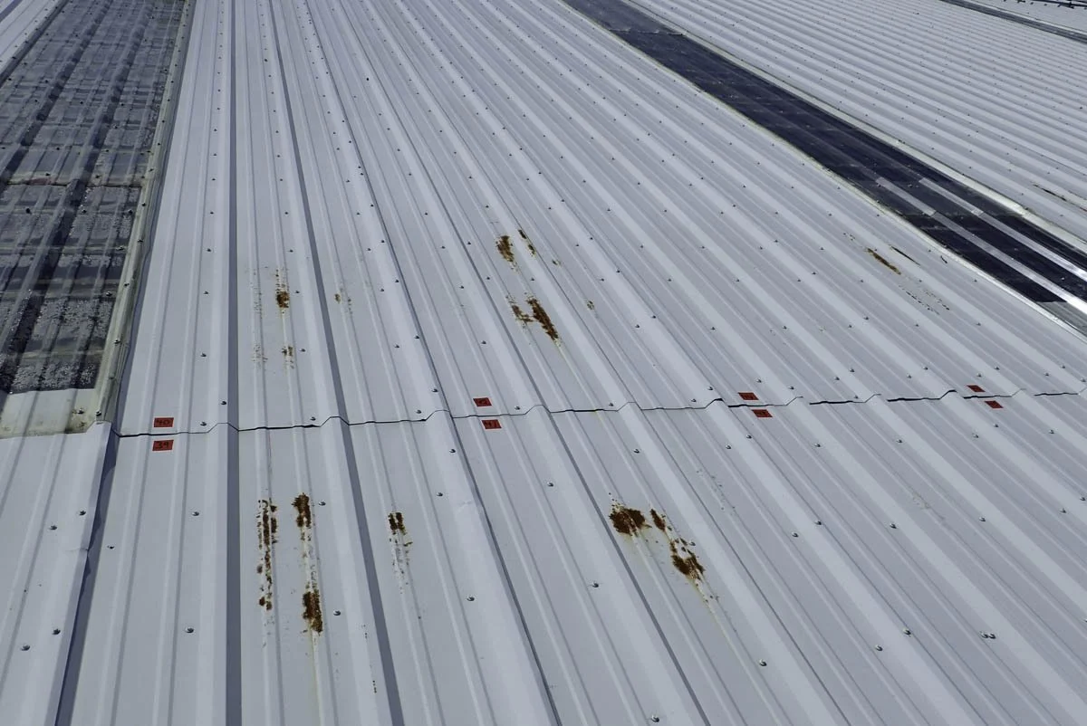 A metal roof with rust spots and two small patches of solar panels on the left side.