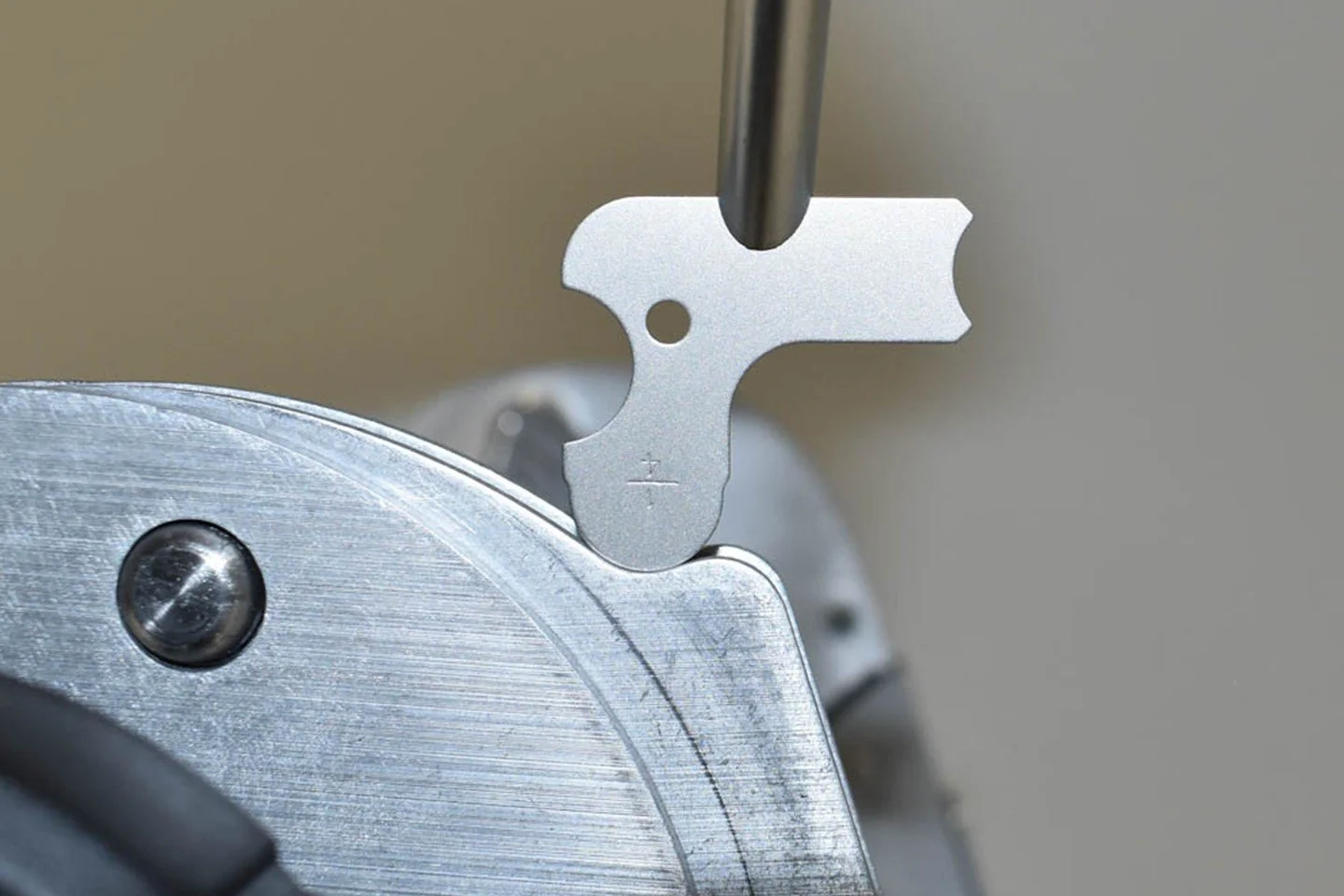 A precision tool being used to make a cut or adjustment on a metallic component, possibly part of a mechanical or electronic device.