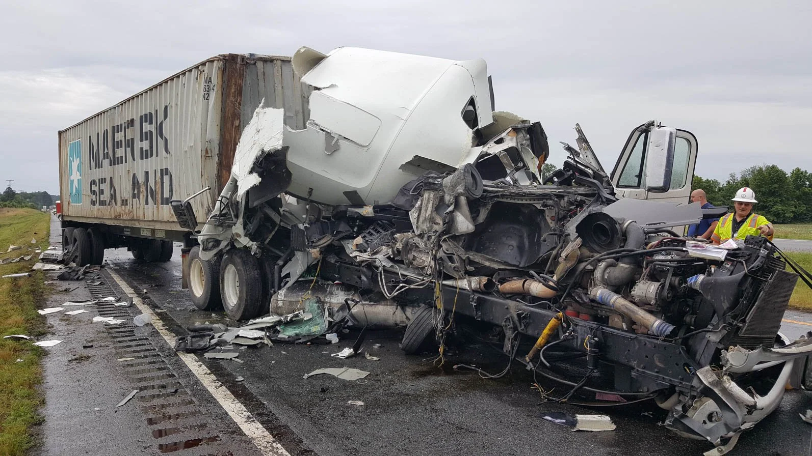 Aerial view of multiple tractor-trailers involved in a roadway crash, including a white tractor and intermodal shipping container trailers, showing vehicle damage and debris across the scene.