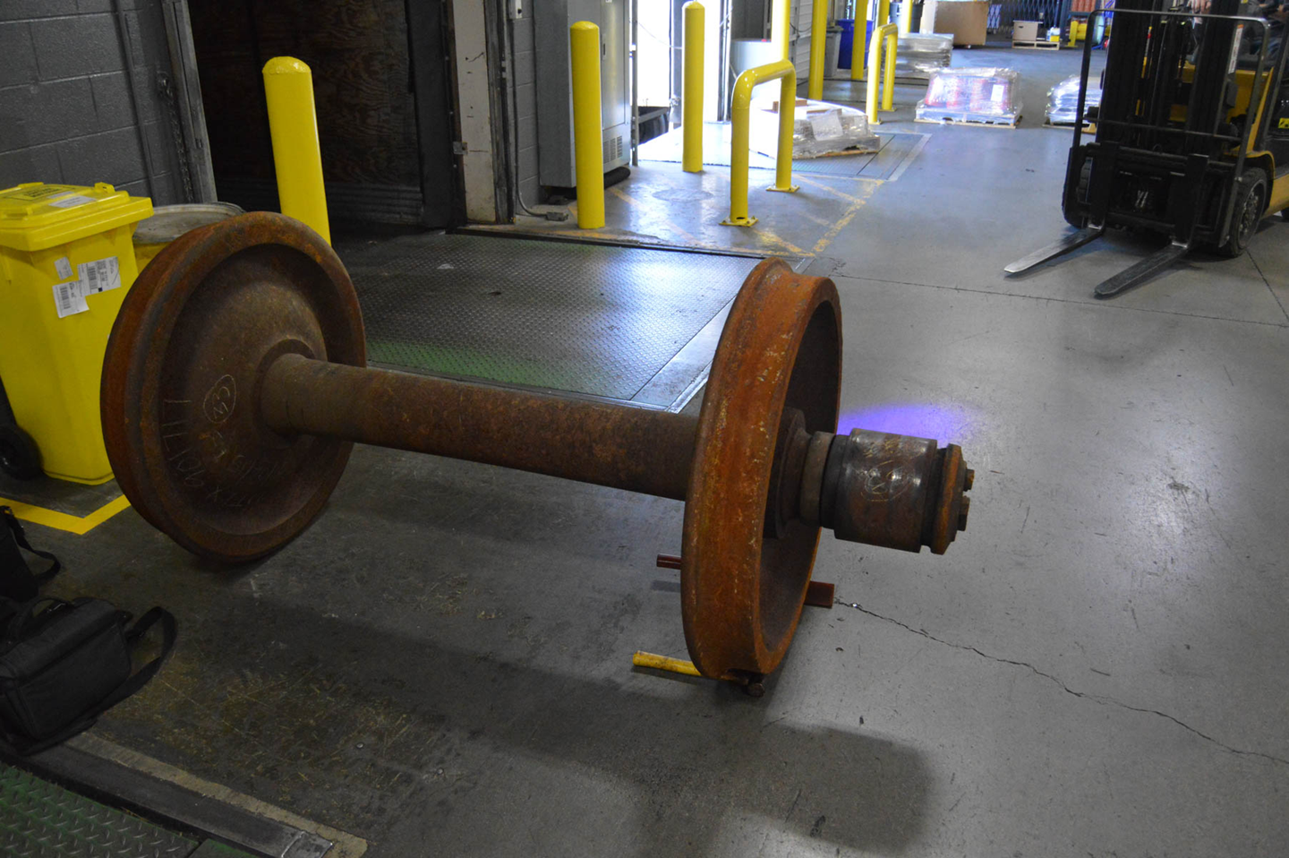 Large rusty cylindrical industrial roller lying on the concrete floor inside a warehouse or industrial facility.