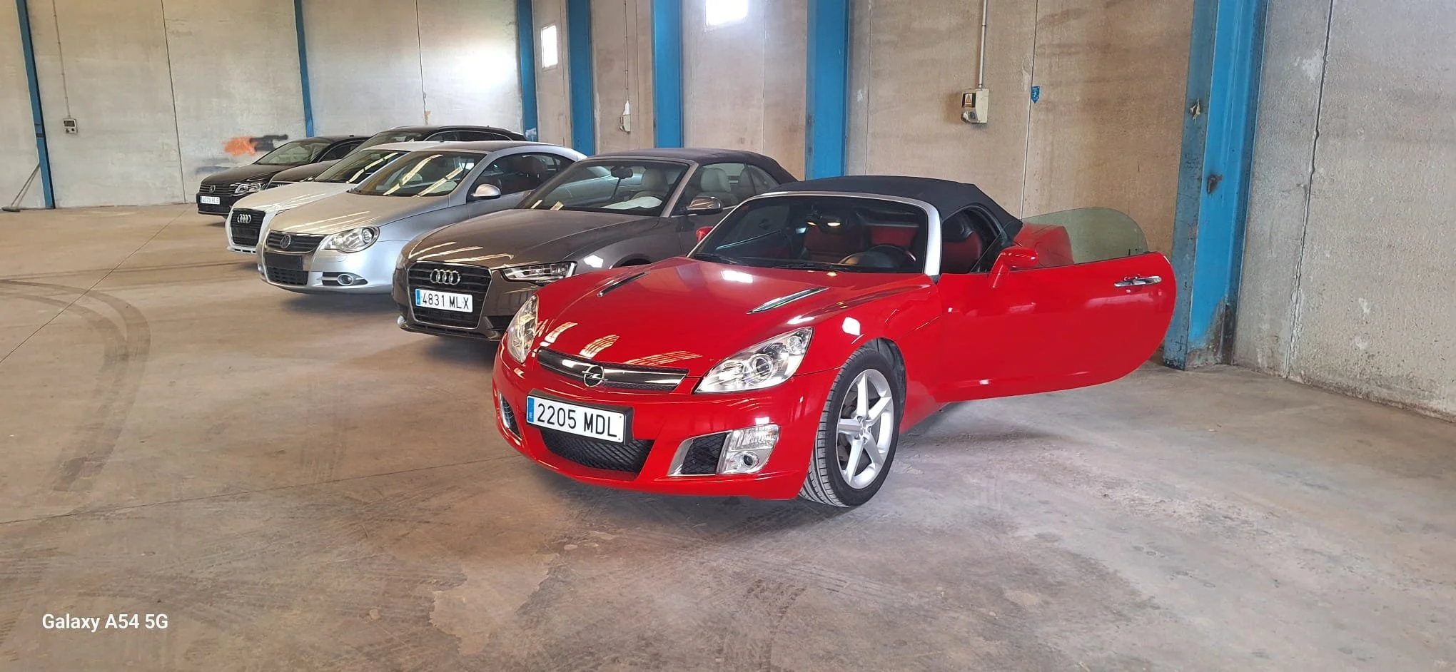 Interior of a silver van showing two rows of seats, with the driver's seat and dashboard on the right side and a three-seater bench on the left side.