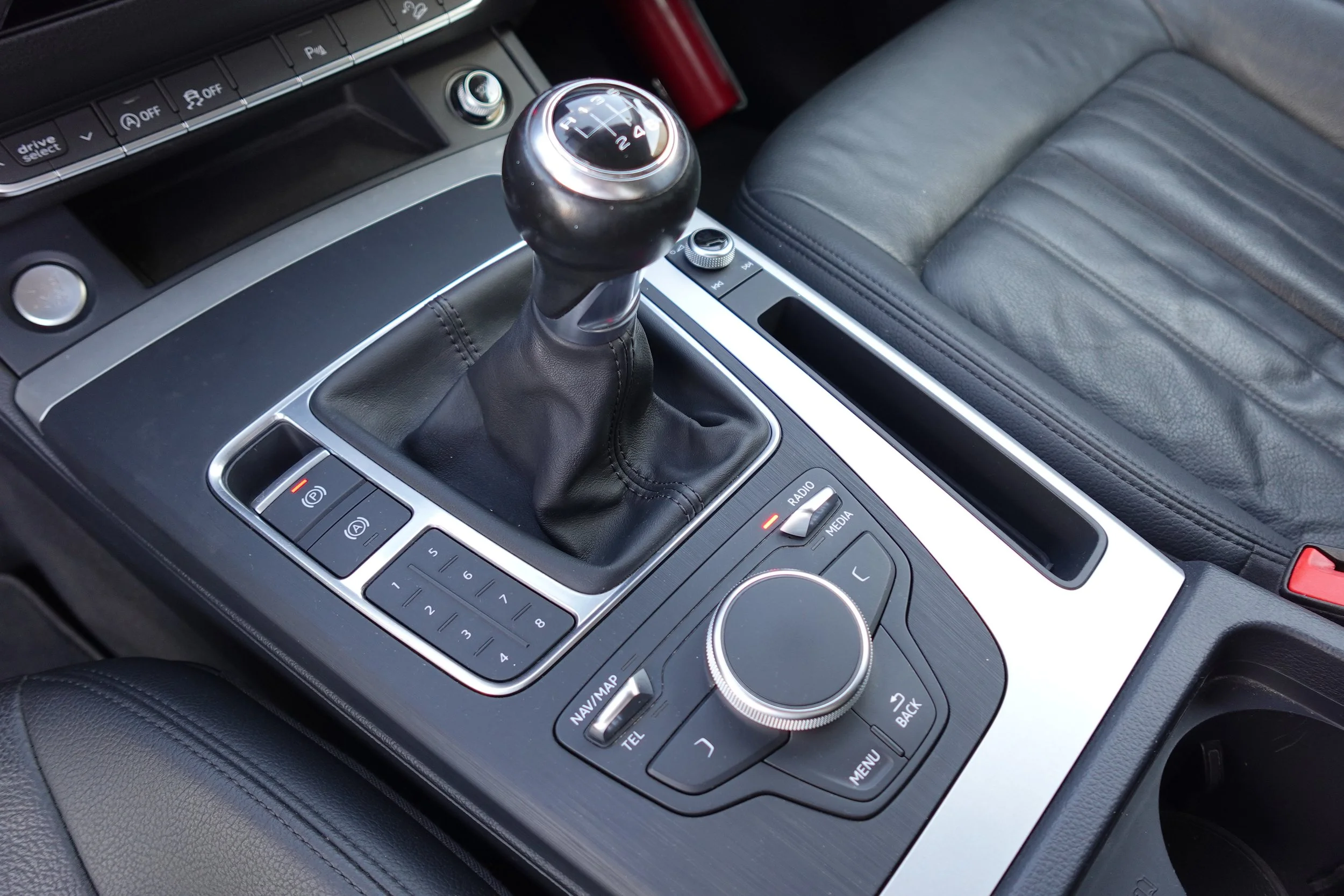 Interior of a car featuring a manual gear shift, control knobs, and buttons on the center console.