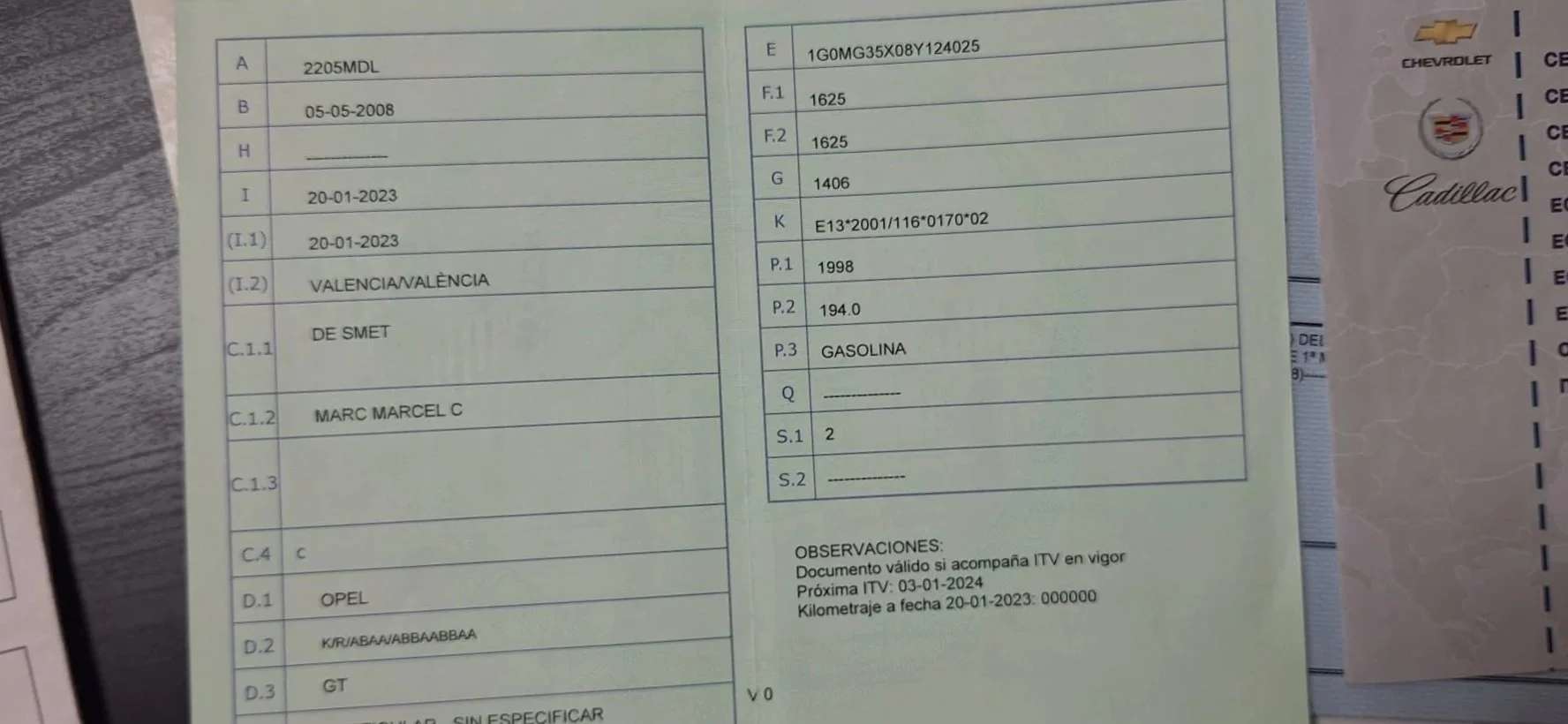 A car inspection report and a vehicle registration document on a gray surface, with a small calculator placed on top of the registration paper.