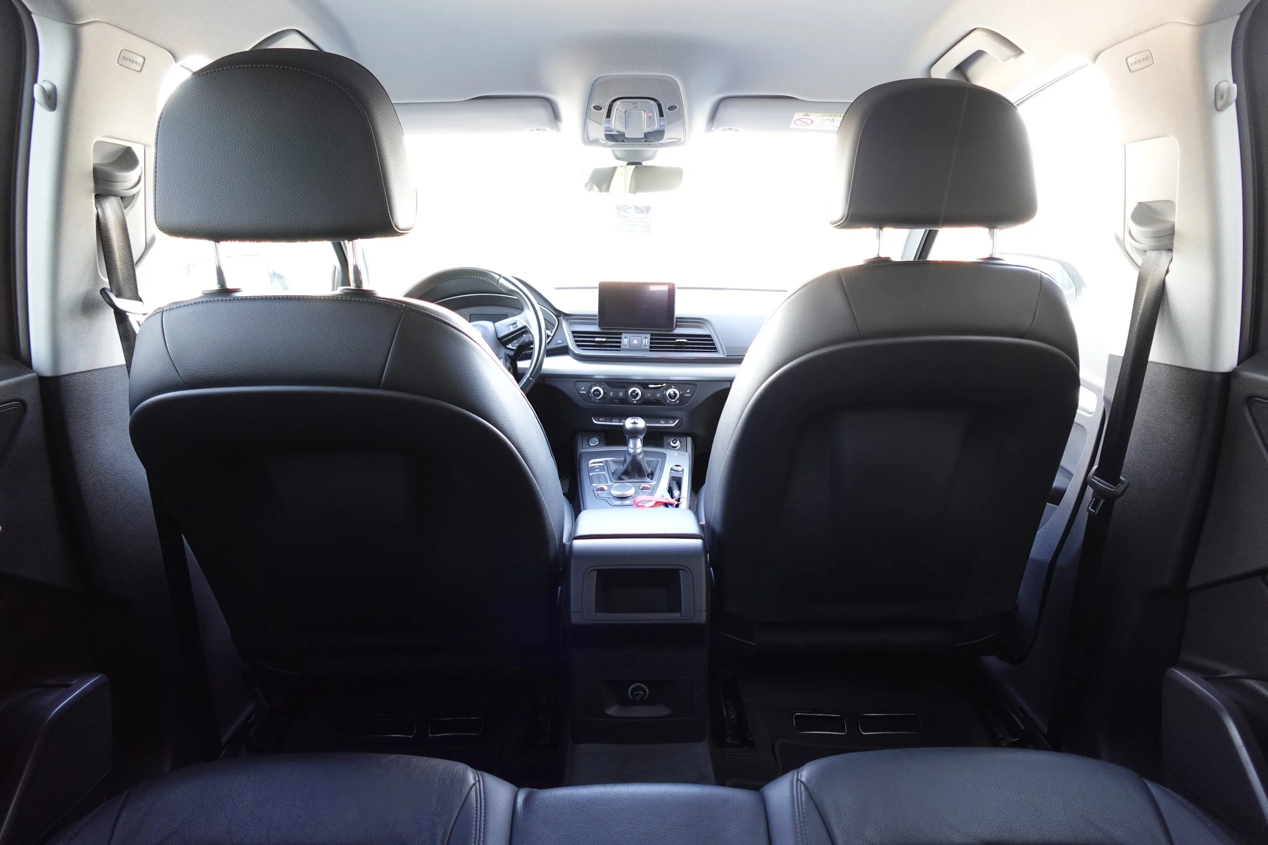 Interior view of a modern vehicle showing the front two seats, dashboard, center console, gear shift, and a small display screen.