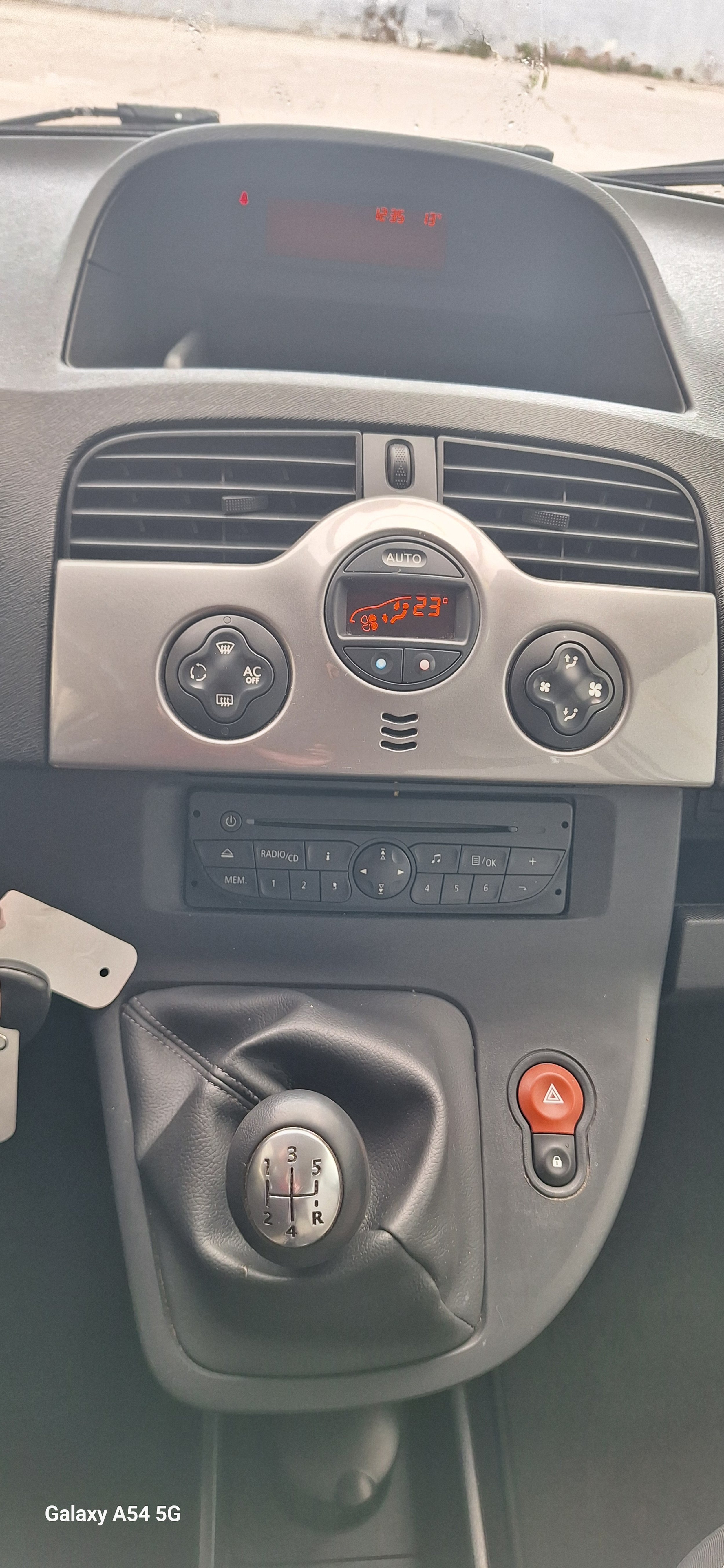 The interior dashboard of a vehicle showing climate control and gear shift, with a digital display showing the temperature set at 23°C and the vehicle is in neutral.