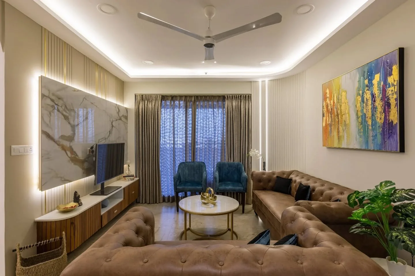 Sometimes calm can be bold too. In this flat, chocolate-toned sofas sit quietly against cream walls while a blue lounger breaks the monotony with flair. Each bedroom tells its own story &mdash; from circular lighting in monochrome tones to deep navy 