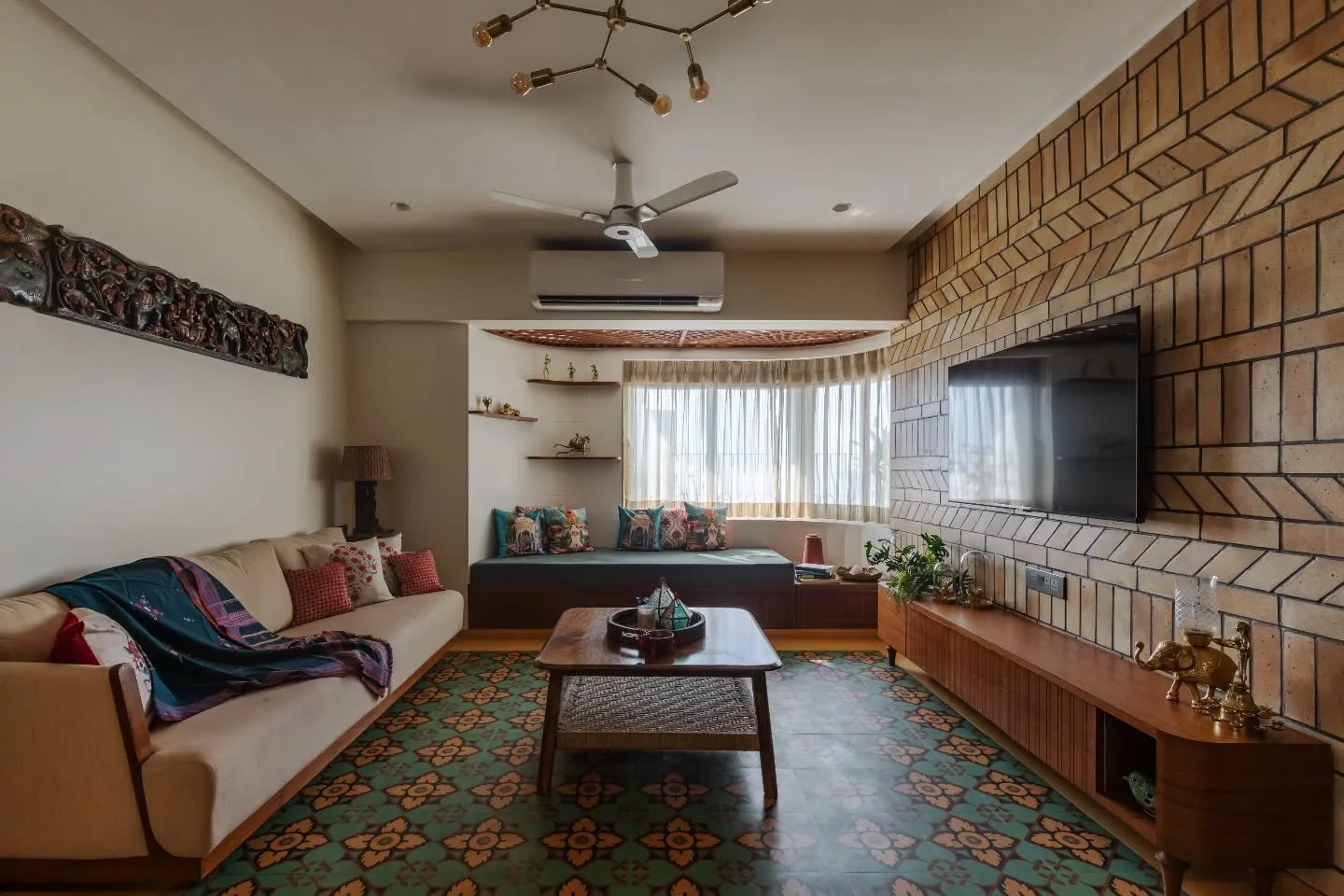 Every corner in this home feels like a quiet conversation between colour and craft. The blue entry sets the tone, leading into a teal patterned floor edged with Jaisalmer stone and a brick wall that glows under warm light. The living brings wood, met