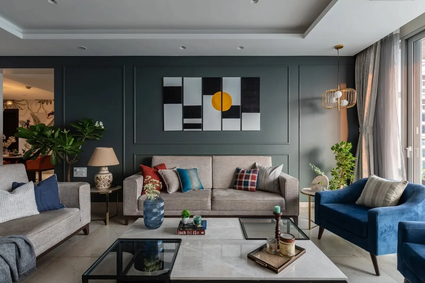 This is where conversation and colour find common ground. Beige sofas and blue loungers circle a marble-glass centrepiece, anchored by dark grey walls and art that hits just right. Opposite, wood and metal frame a display that steals attention withou
