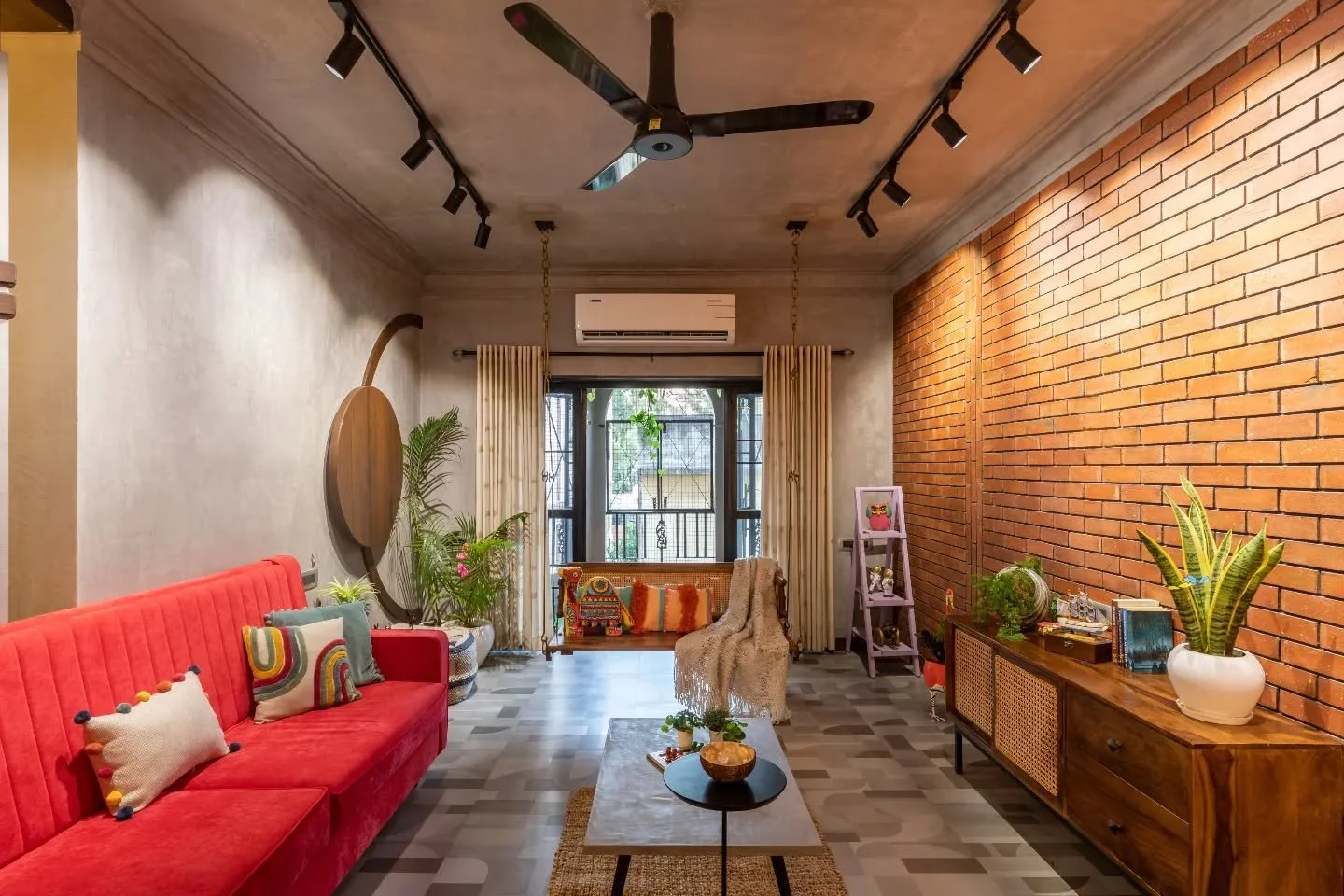 There&rsquo;s an effortless mix of grit and grace here. Exposed brick meets motif flooring, a red lounger anchors the living, and cane details soften the edges. The dining stays grounded in grey and the kitchen shifts to green. Even the calm bedroom 