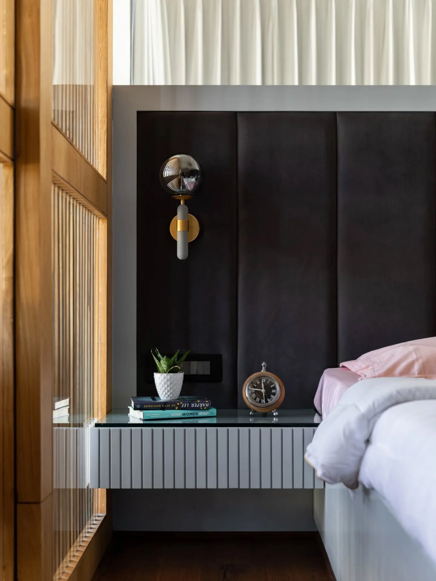 These rooms feel less like enclosed spaces and more like observatories for the garden outside. Walls dissolve into windows, wooden floors ground the interiors, and furniture seems arranged for lingering rather than sleeping. One bedroom experiments w