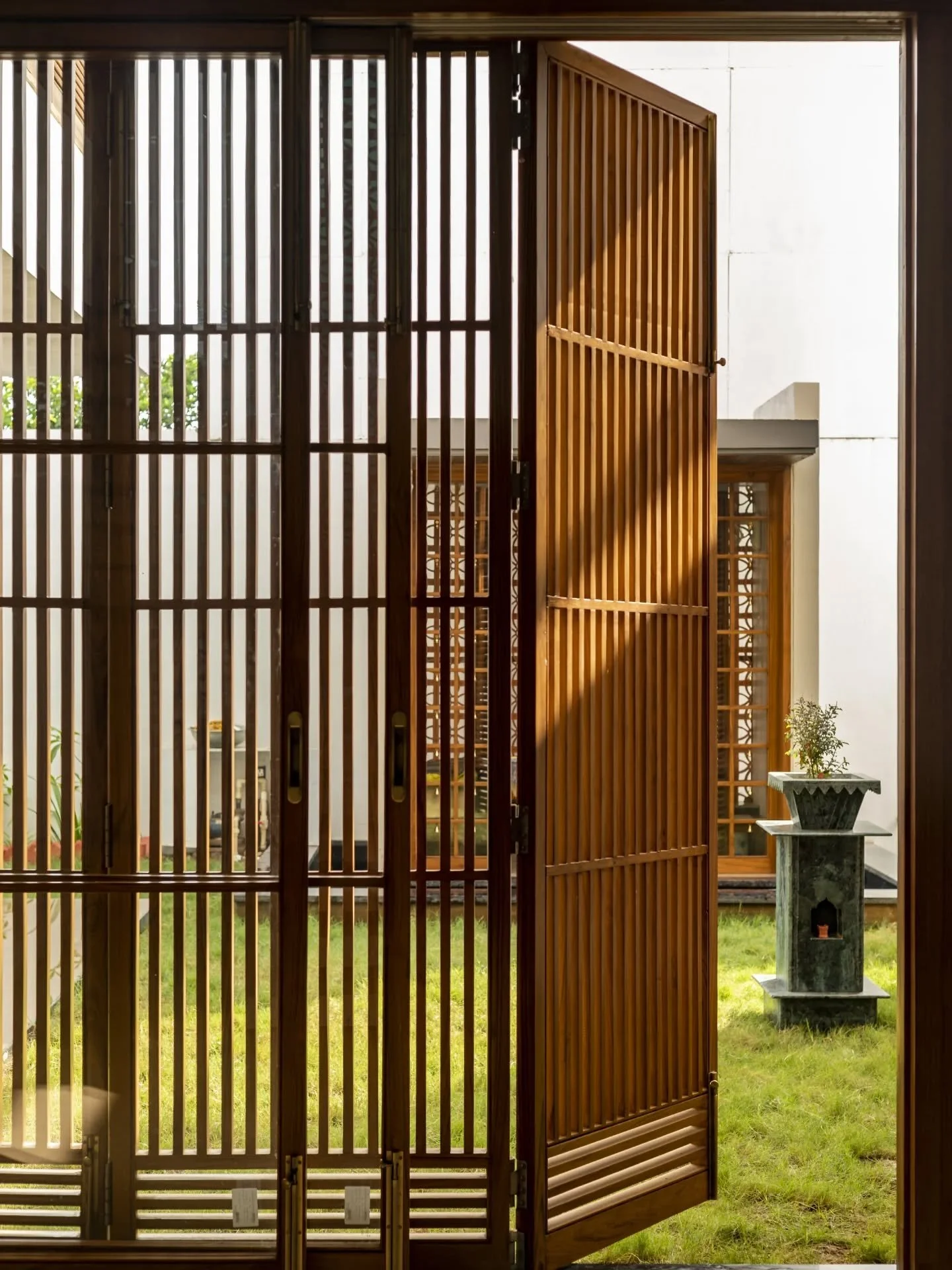 This bungalow sits comfortably between two worlds without needing to choose sides. A restrained facade of grey and white opens into a house where wood takes over quietly&mdash;filtering light, shaping views, and holding everything together. Spaces fe