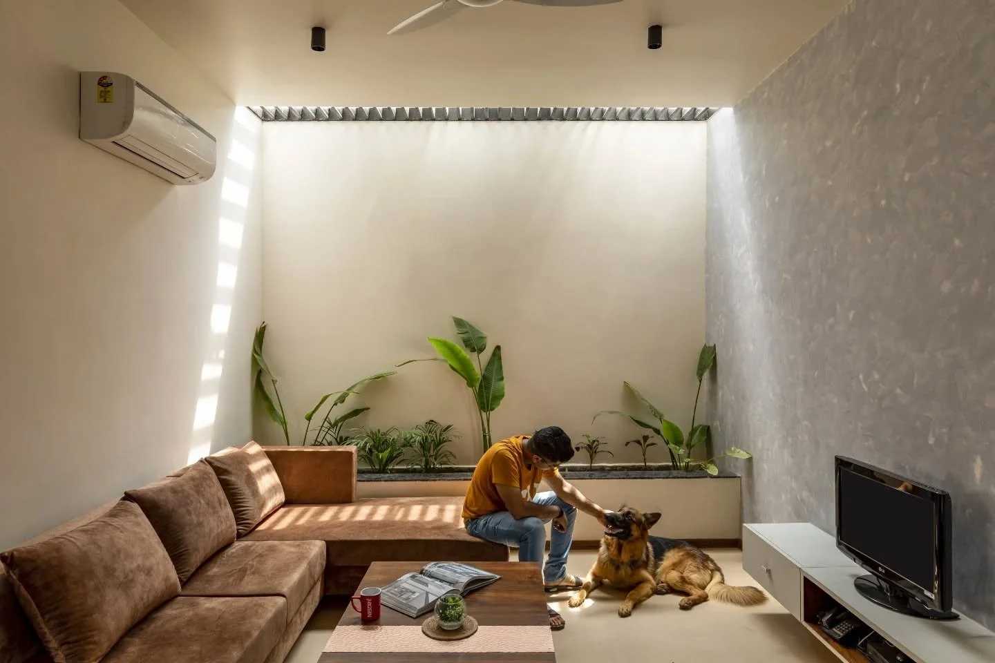 Inside, the house keeps things open but never empty. White surfaces carry light across the rooms, wooden furniture anchors the spaces, and jaali elements gently divide without closing anything off. The living areas flow into one another with ease, al