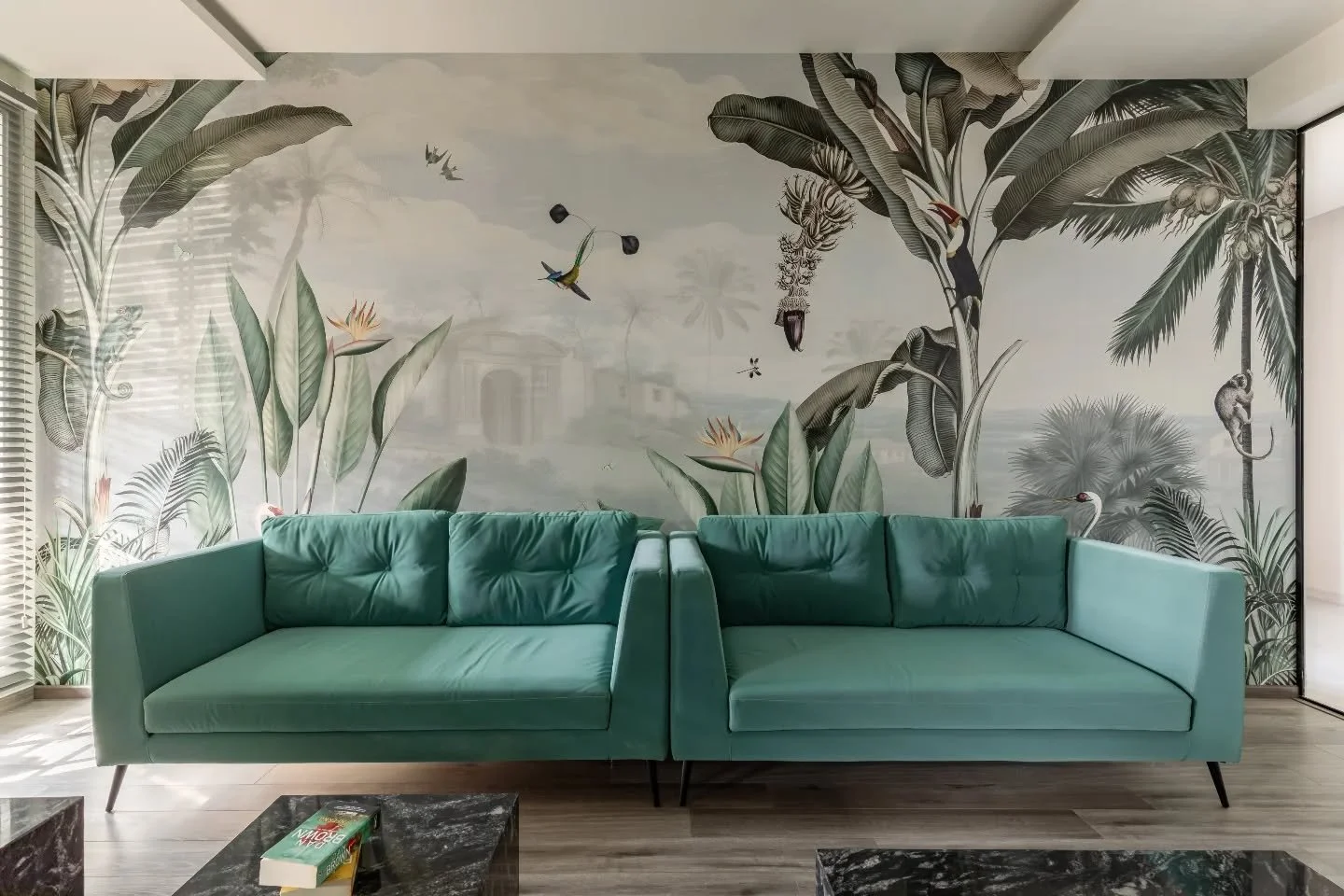 The heart of the home runs in a straight line, but never feels linear. A family lounge settles into greys and wood, edged by a staircase that blends right in. Dining opens up to light and green overhead, softening the geometry, while the kitchen foll