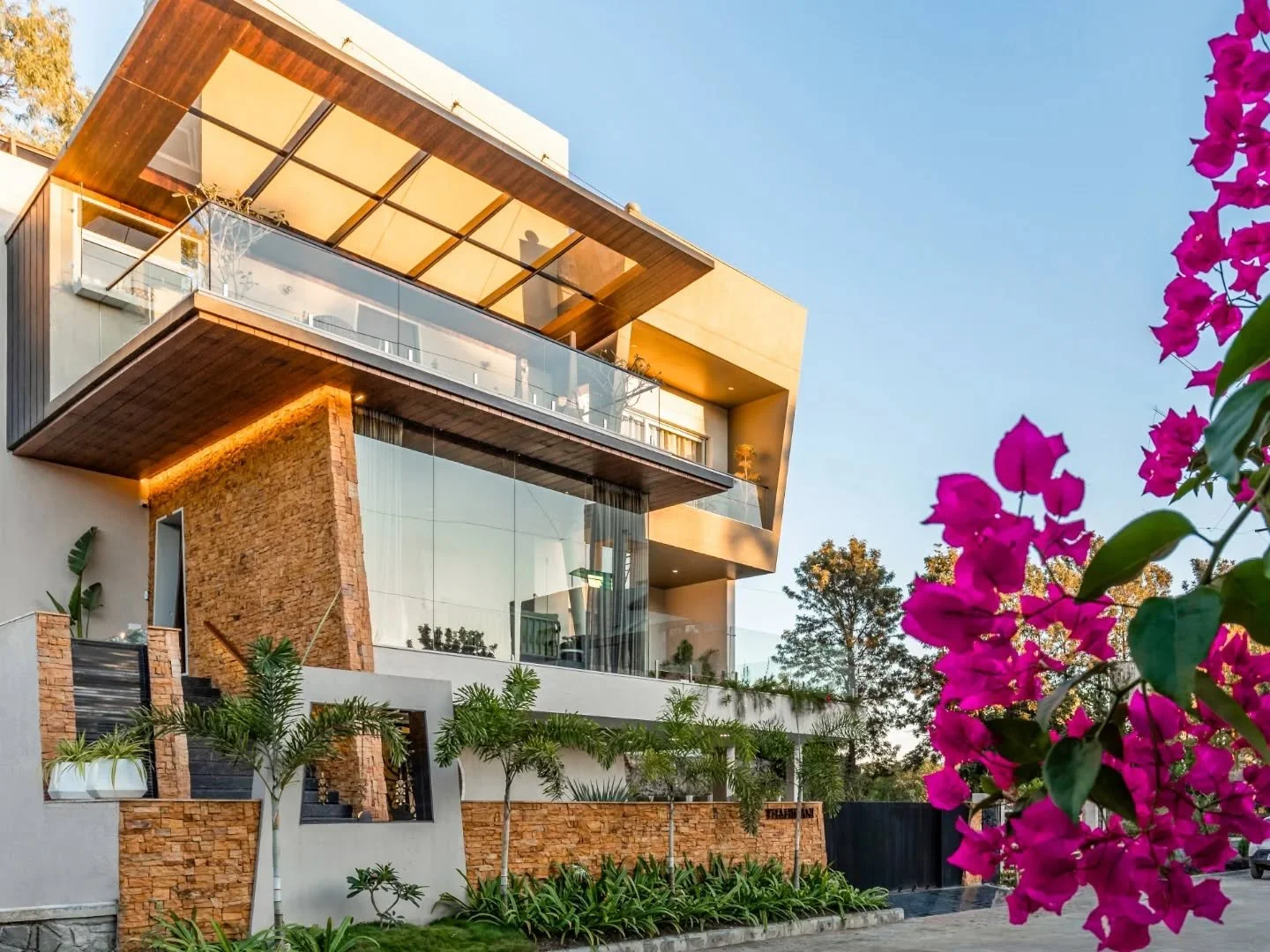 The most interesting conversations in this house happen through materials. Cool stone travels from outside to inside, warm fluted timber softens transitions, and a circular opening between kitchen and dining turns an ordinary wall into a point of int