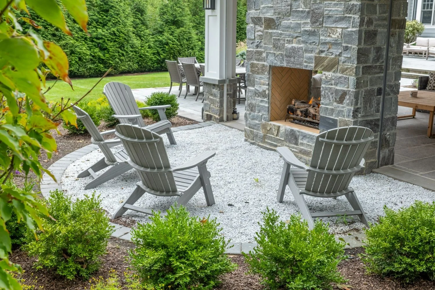 Natural stone detailing surrounds a fire pit in a landscaped backyard in Ridgewood, NJ
