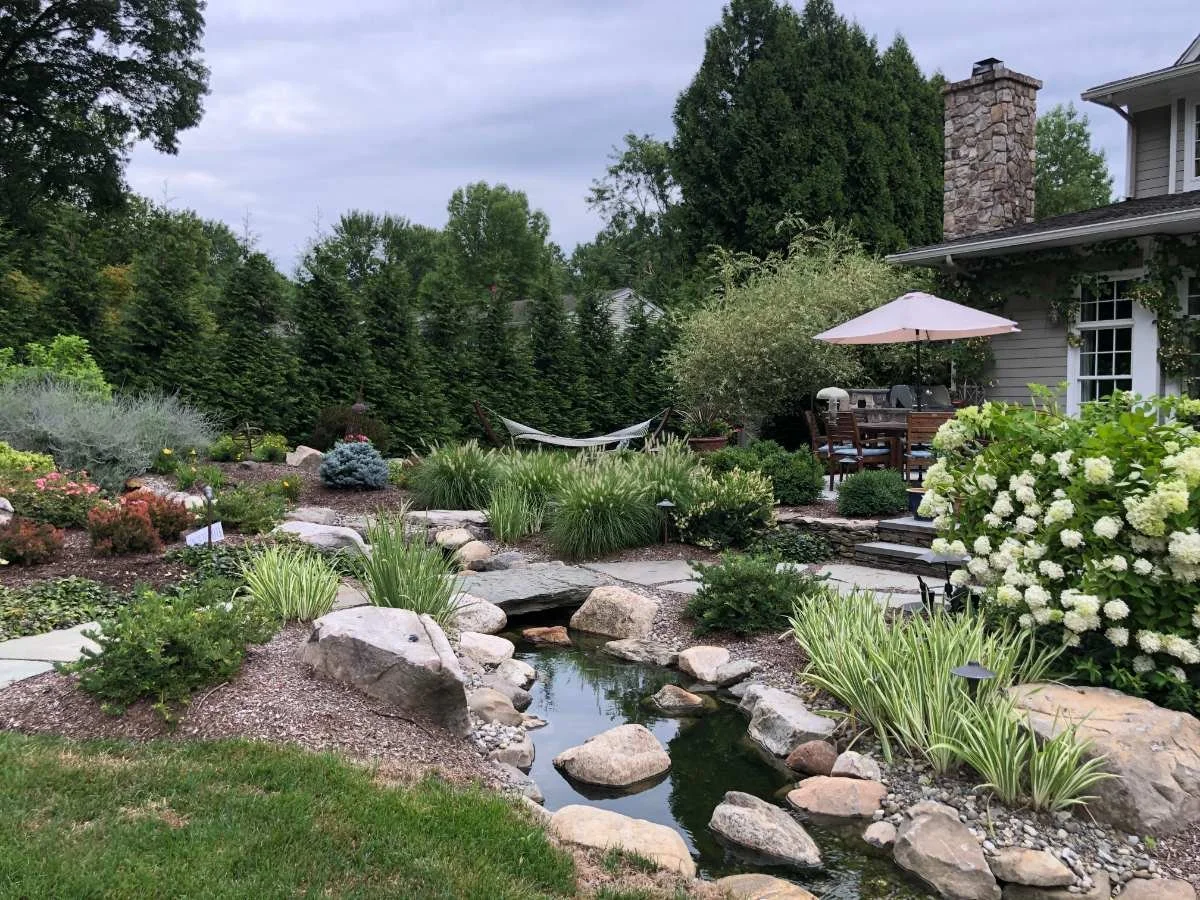 Natural stone stream water feature with a nature pathway  and foor bridge in Allendale, NJ