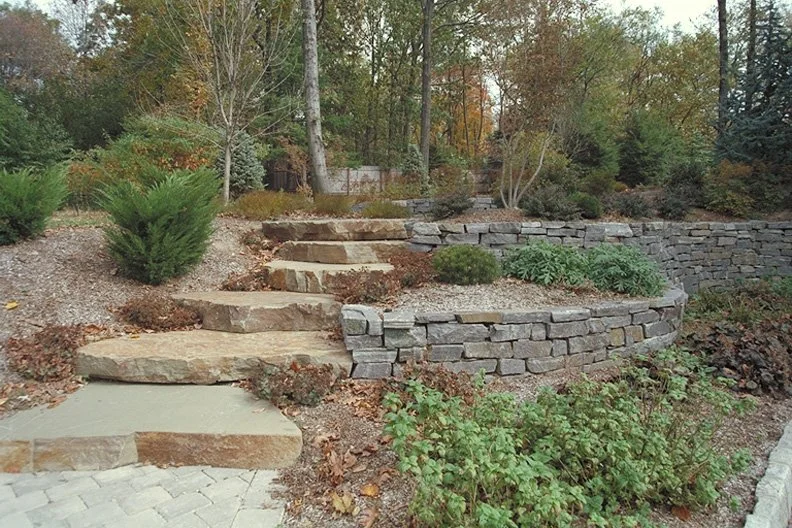 Stone steps and flat slabs shaping a natural pathway through the landscape in Saddle River, NJ