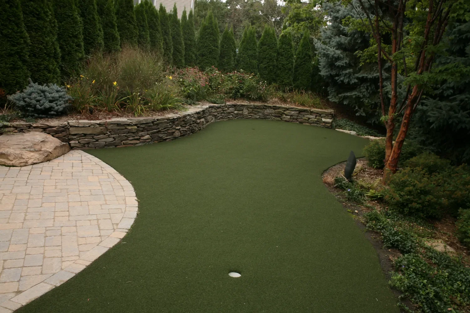 Natural stone retaining wall framing outdoor seating and landscape features in Ridgewood, NJ