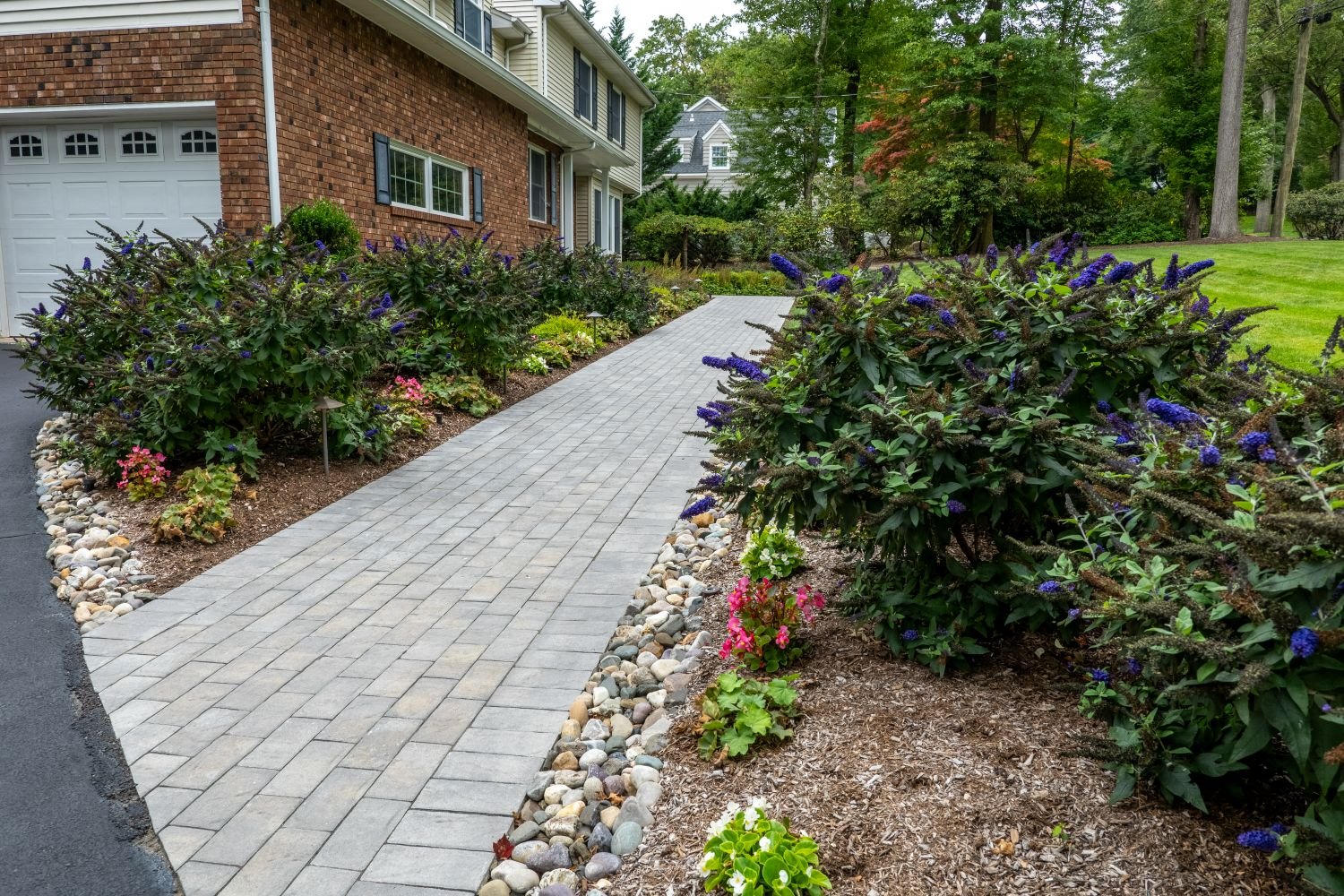 Backyard with decorative river rock drainage path integrated into lush landscaping in Glen Rock, NJ