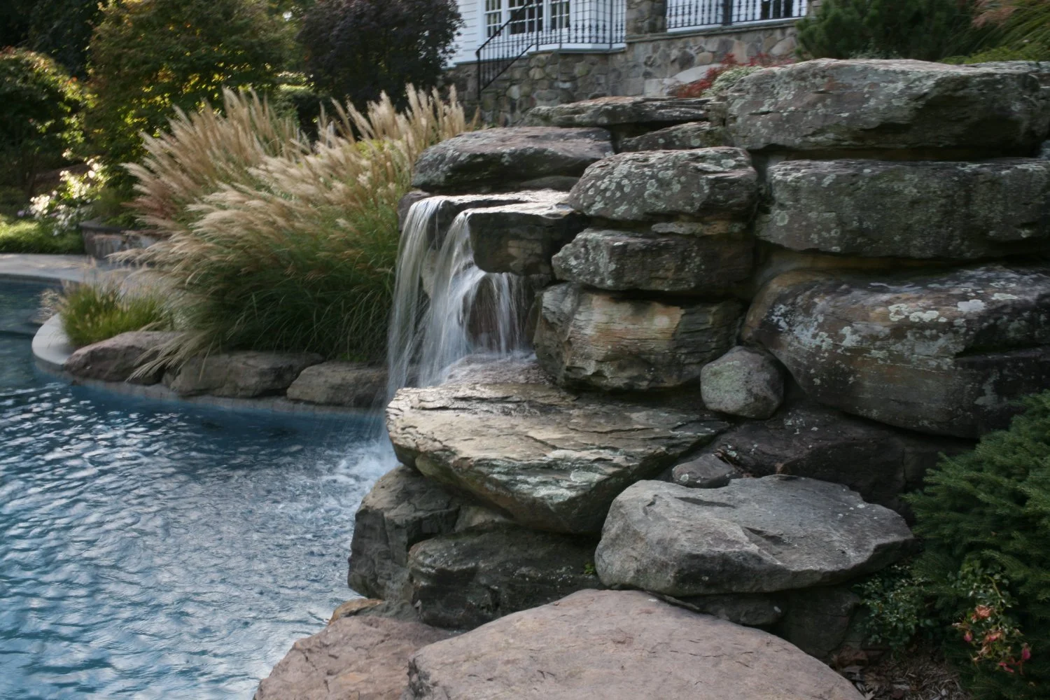 Tiered stone waterfall spilling into a landscaped pond setting in Allendale, NJ