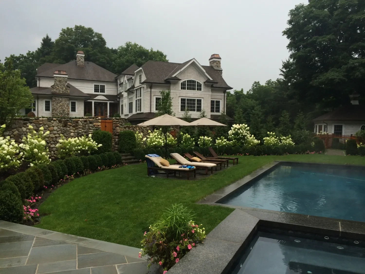 Stone retaining wall supporting elevation changes in a wooded backyard setting in Upper Saddle River, NJ