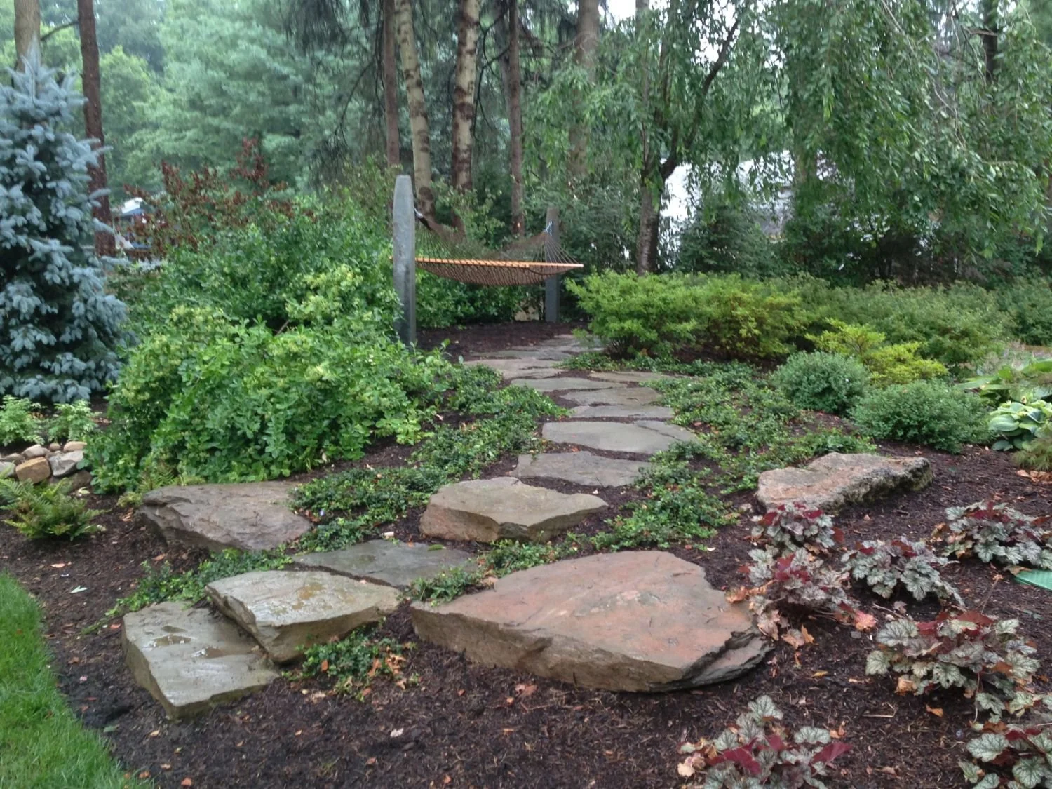 Garden beds framing a natural pathway made of irregular stone in Saddle River, NJ
