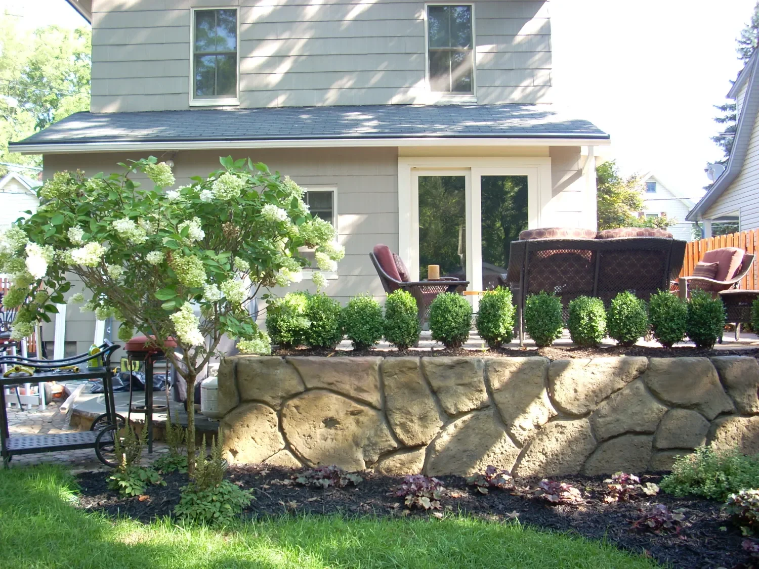 Raised retaining wall creating a clean edge for a backyard patio space in Ridgewood, NJ