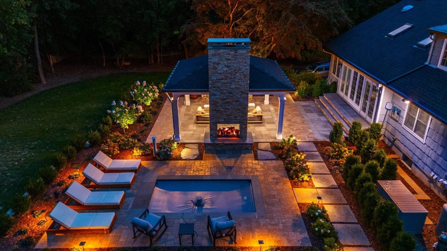 Evening landscape lighting accenting architectural details around the home in Franklin Lakes, NJ