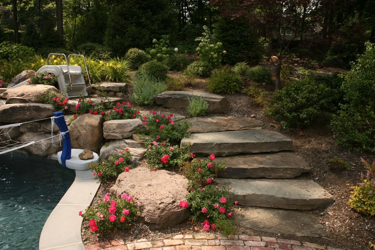 A natural pathway leading toward a seating area and garden feature in Saddle River, NJ