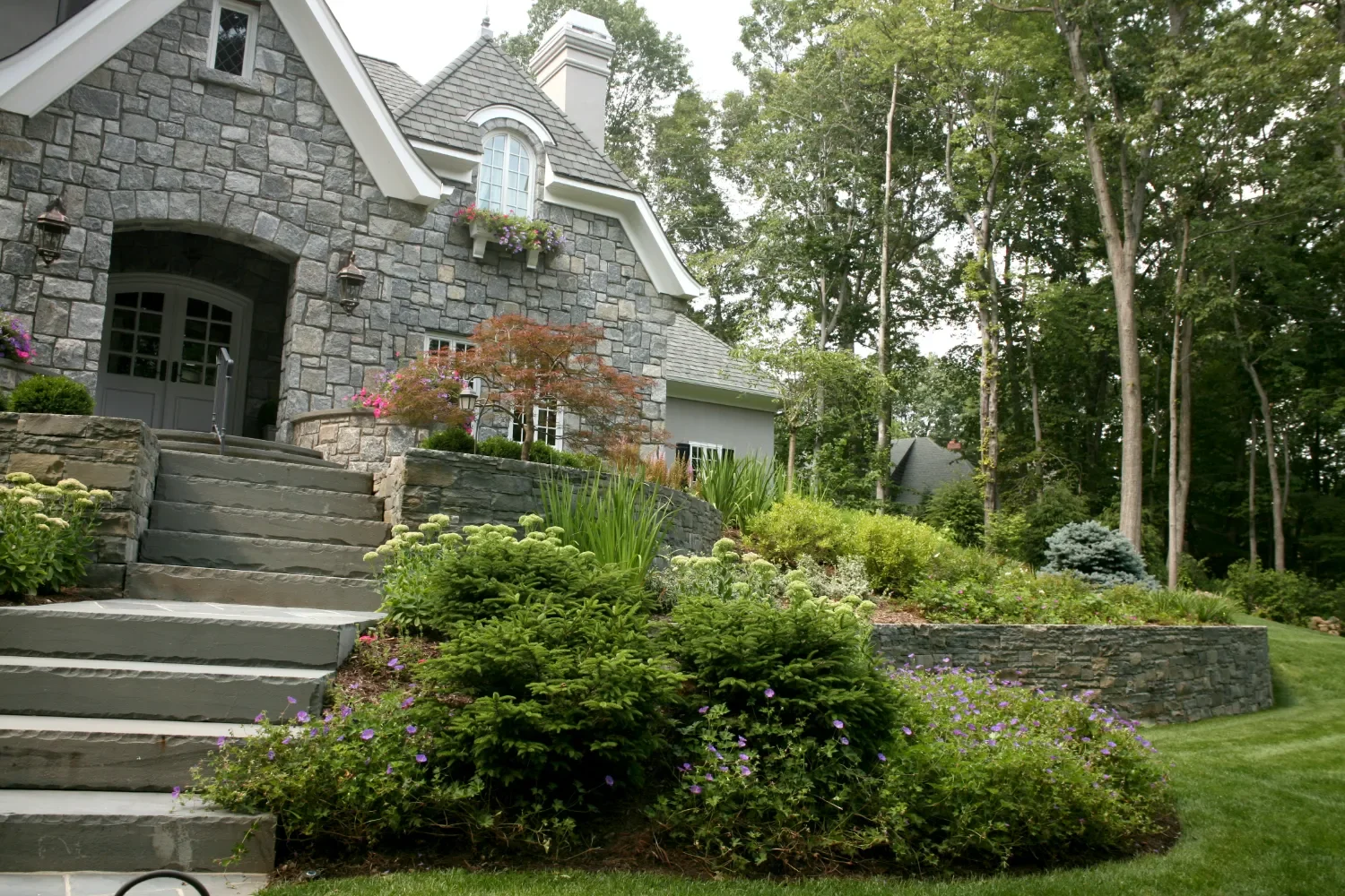 Low retaining wall constructed from natural stone bordering a landscaped lawn in Oradell, NJ