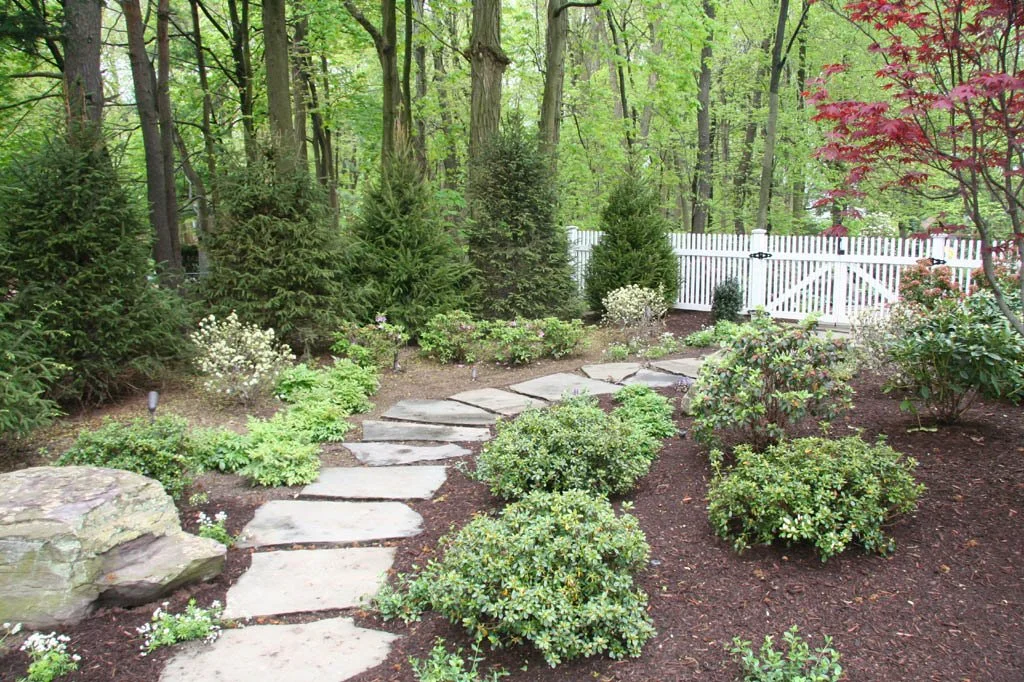 Flat stone slabs arranged as a natural pathway leading toward a gated yard in Saddle River, NJ