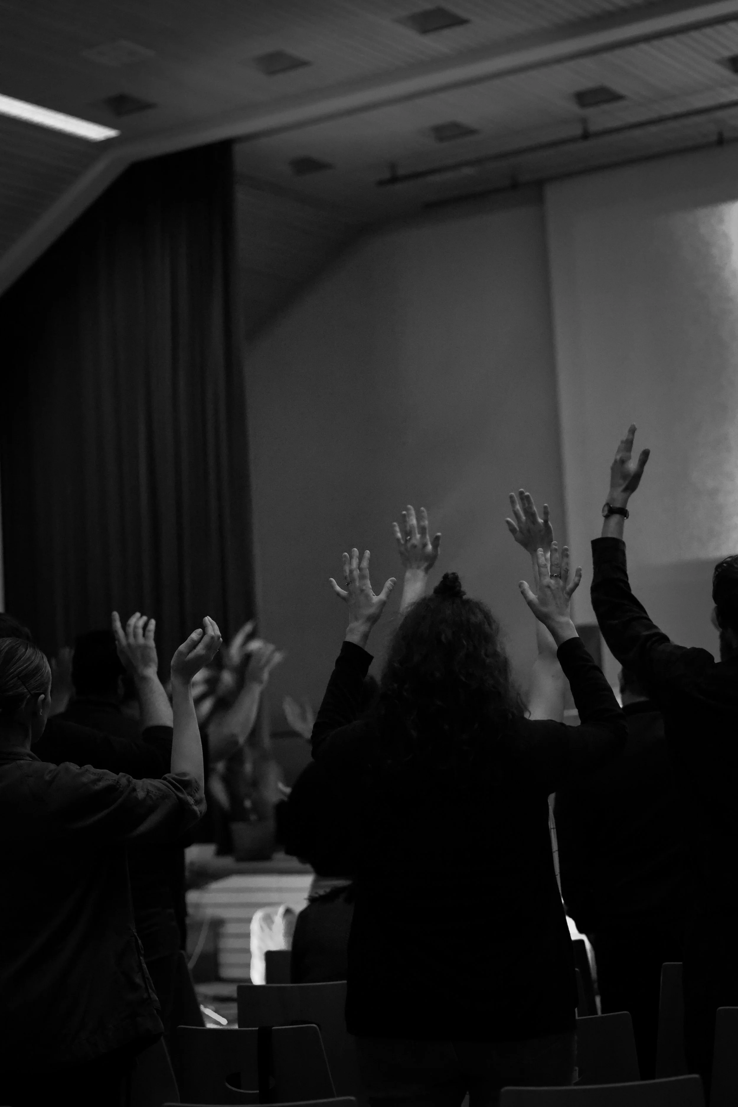Three friends standing outdoors on a sunny day, smiling and with arms around each other.