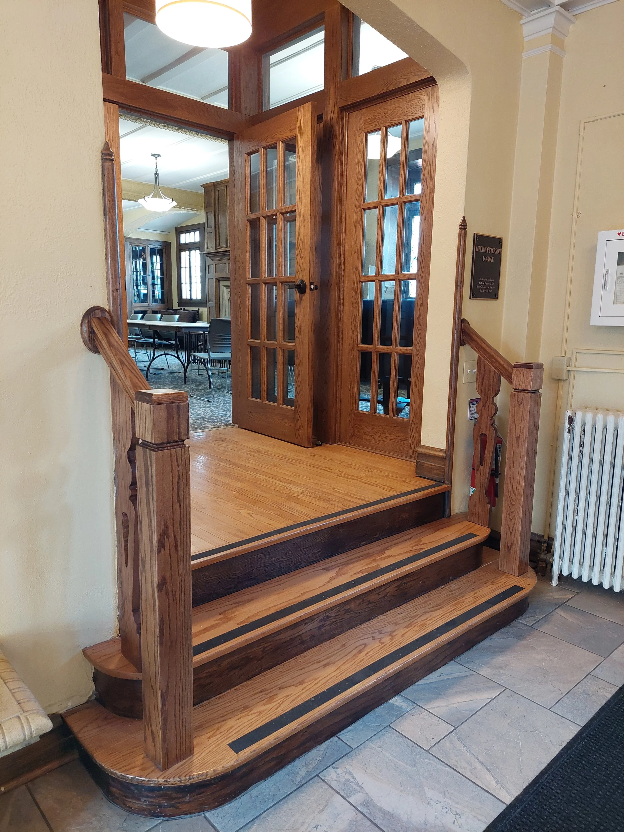 Wooden staircase with three steps leading to French doors; interior with wooden trim and glass panes.