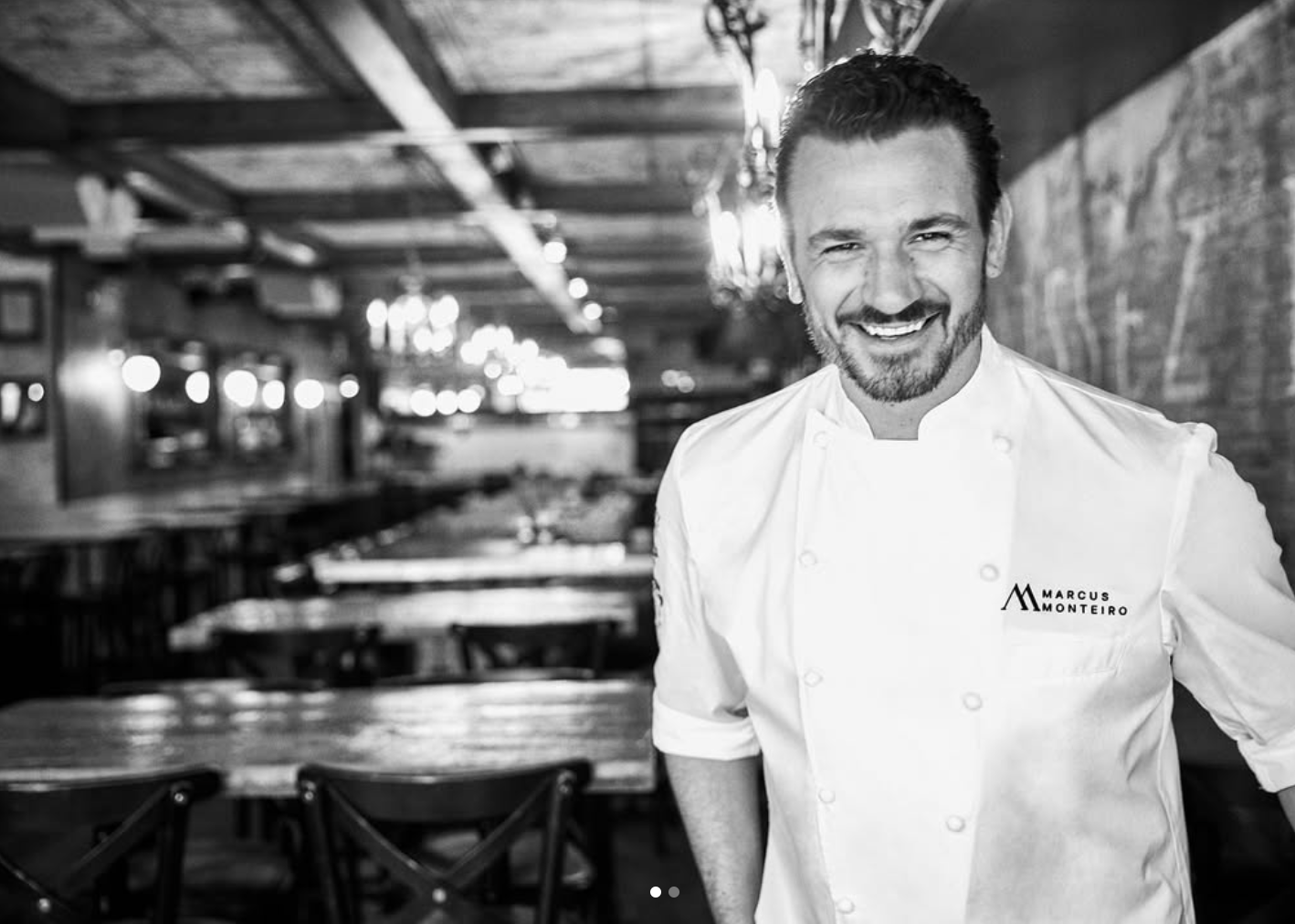 Chef Marcus Monteiro smiling in a restaurant dining room