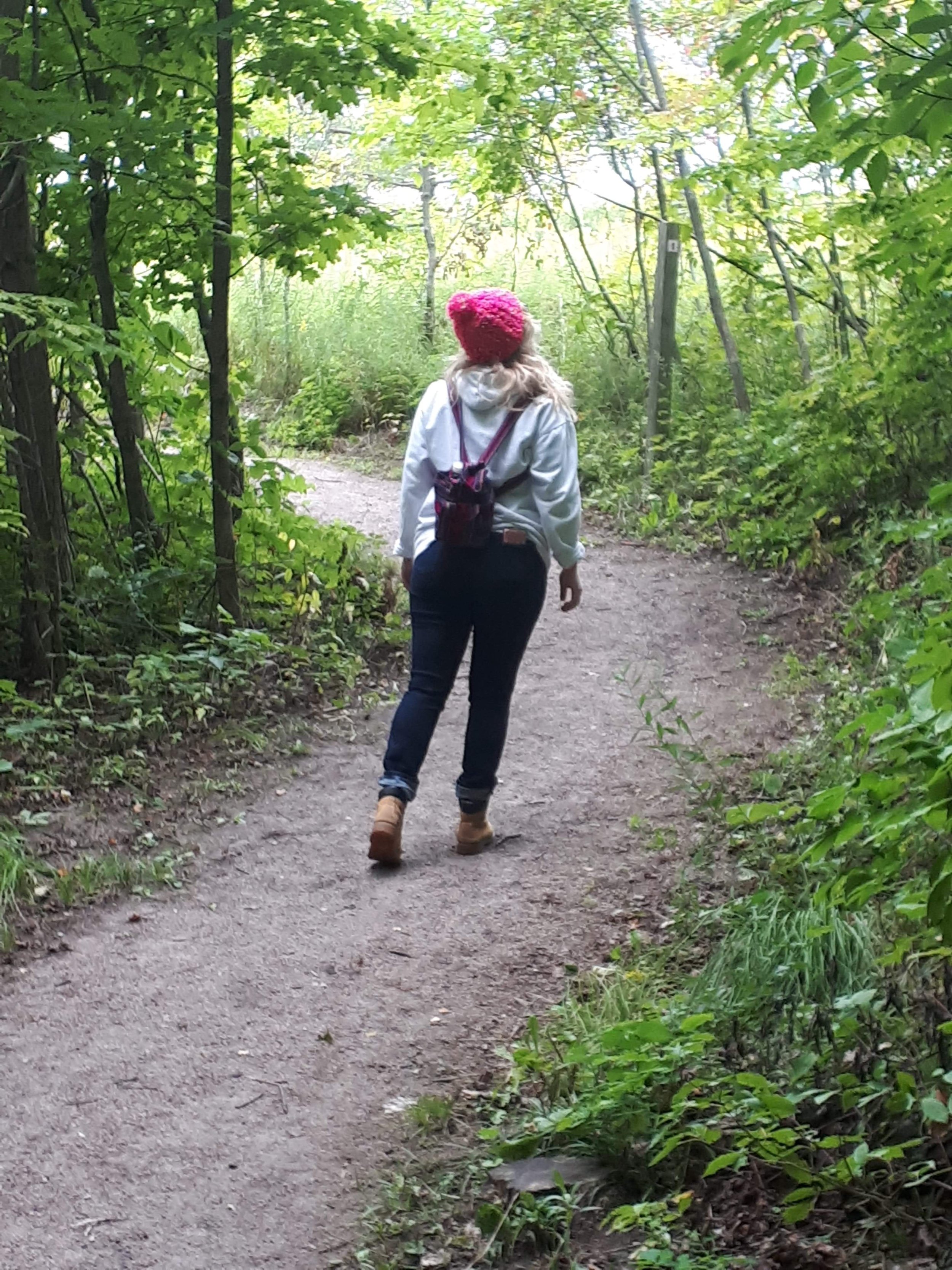 Person in a pink hat walking on a wooded path
