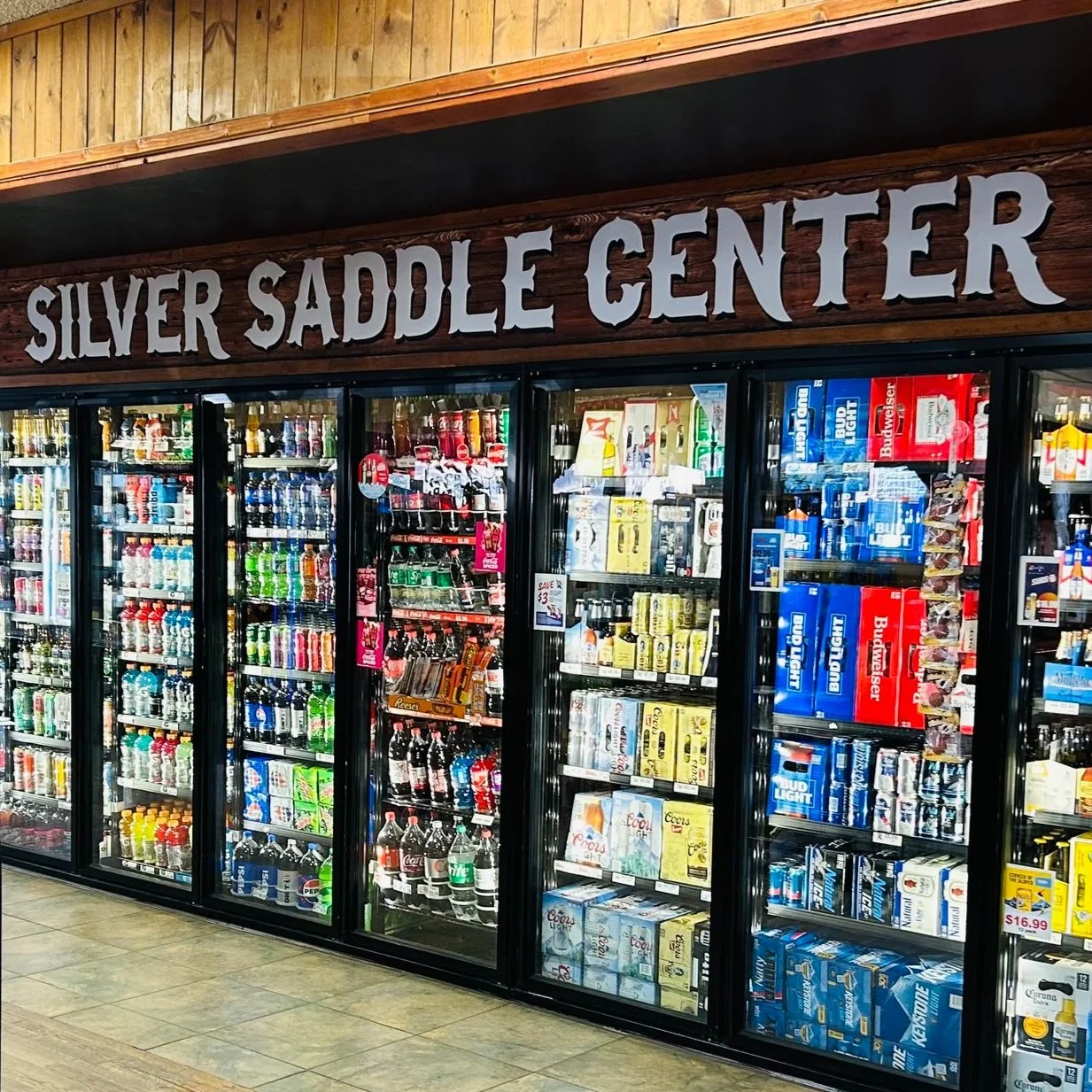 Refrigerator section at Silver Saddle Center with various beverages including soda cans and bottles, beer boxes, and alcoholic drinks.