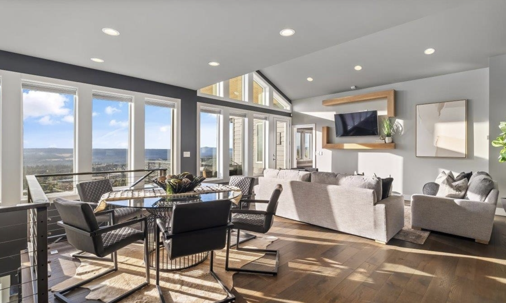 Staged living and dining room with floor‑to‑ceiling windows overlooking the Inland Northwest, illustrating local staging results