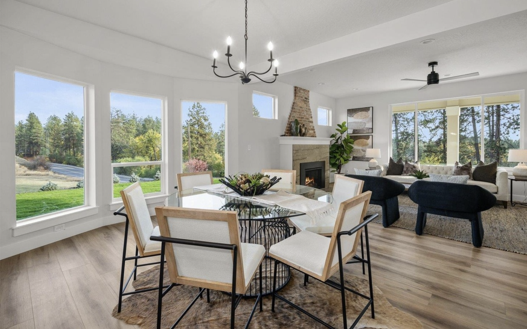 Professionally staged open‑concept living and dining room in Spokane with floor‑to‑ceiling windows, a stone fireplace and neutral furnishings, illustrating how Home Staging Works transforms spaces for Inland Northwest Realtors.