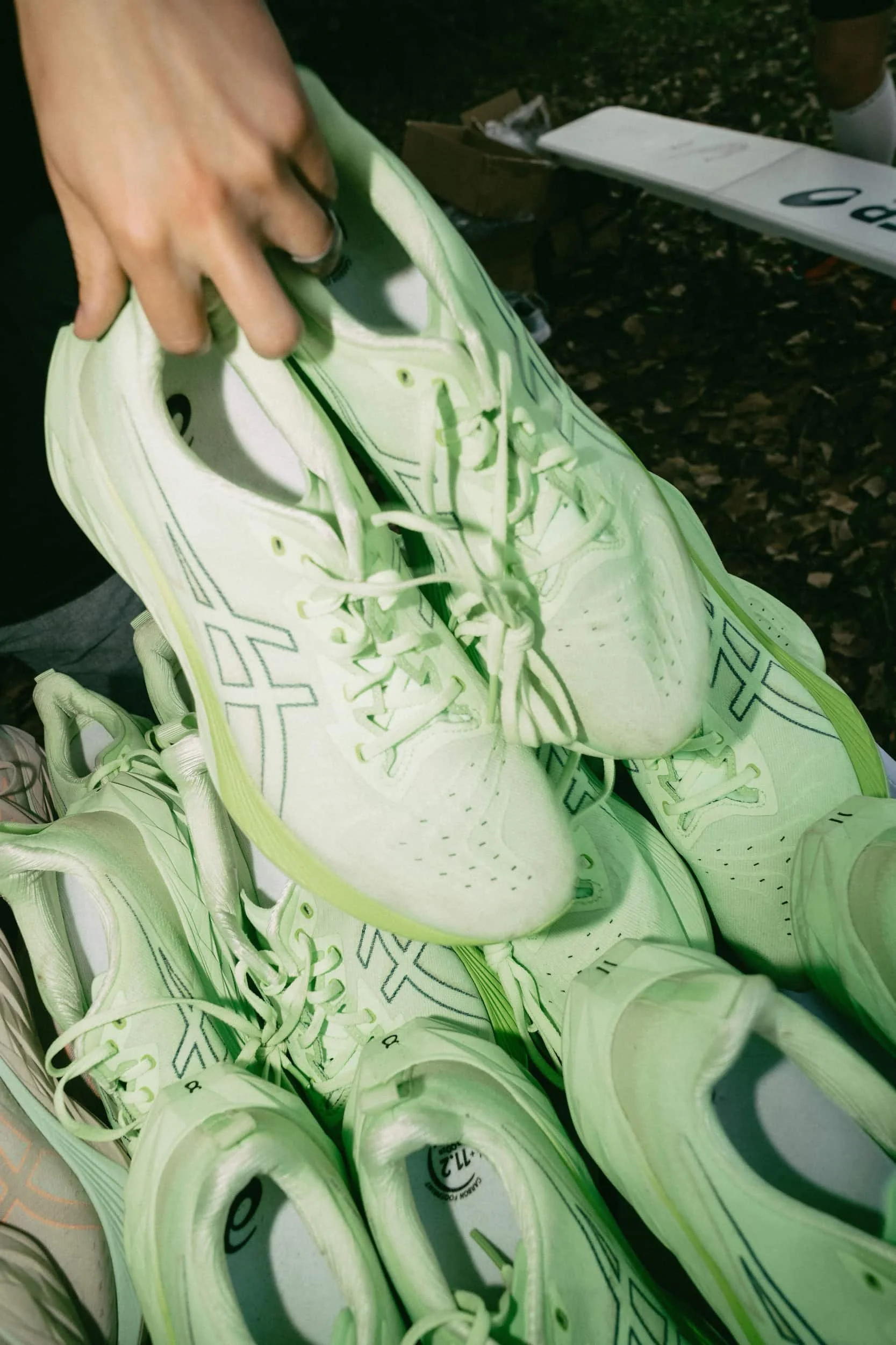 A hand holding a pair of mint green sneakers