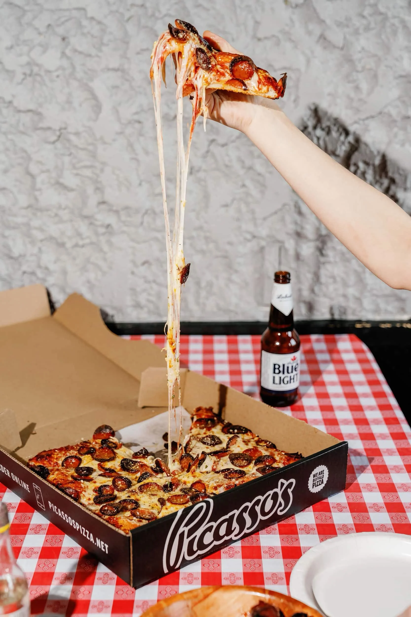A piece of pizza being lifted out of a box with stringy cheese