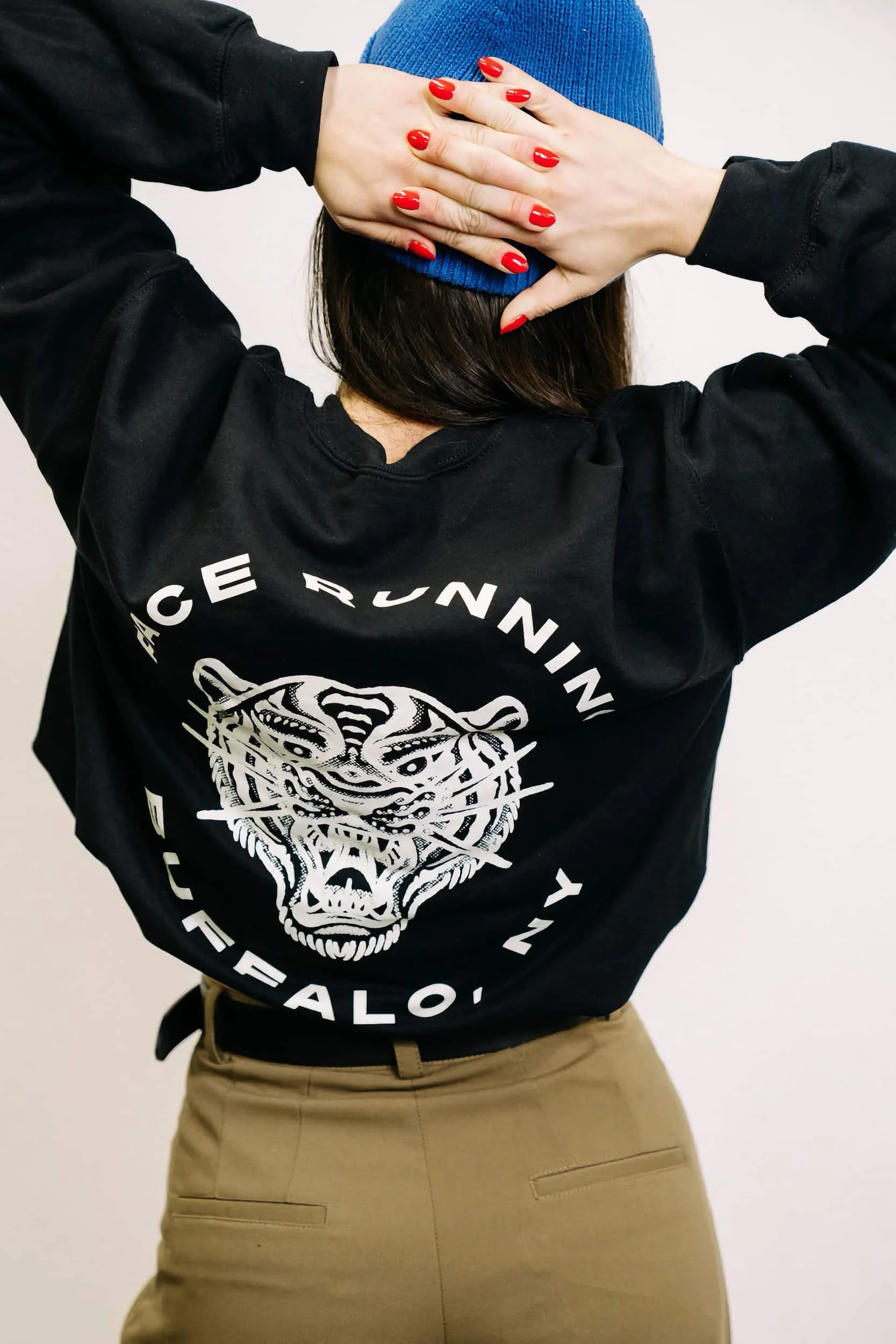 A person with their fingers laced behind their head wearing a Buffalo, NY jacket