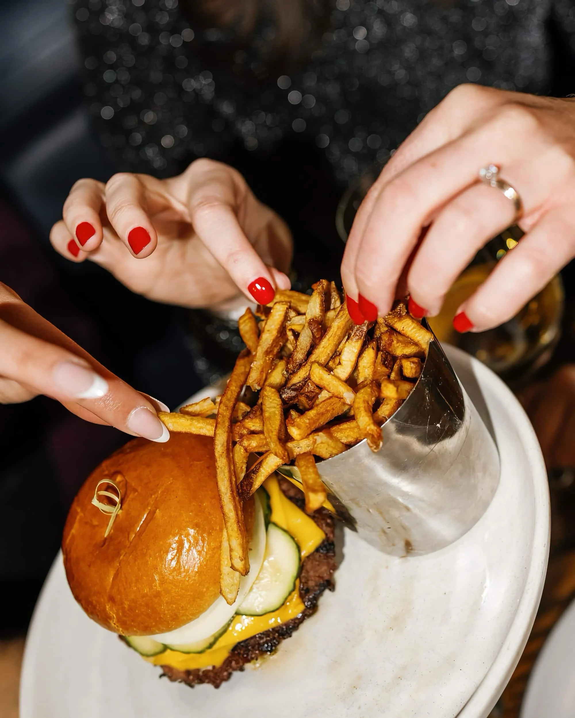 A closeup of women eating a burger and fries
