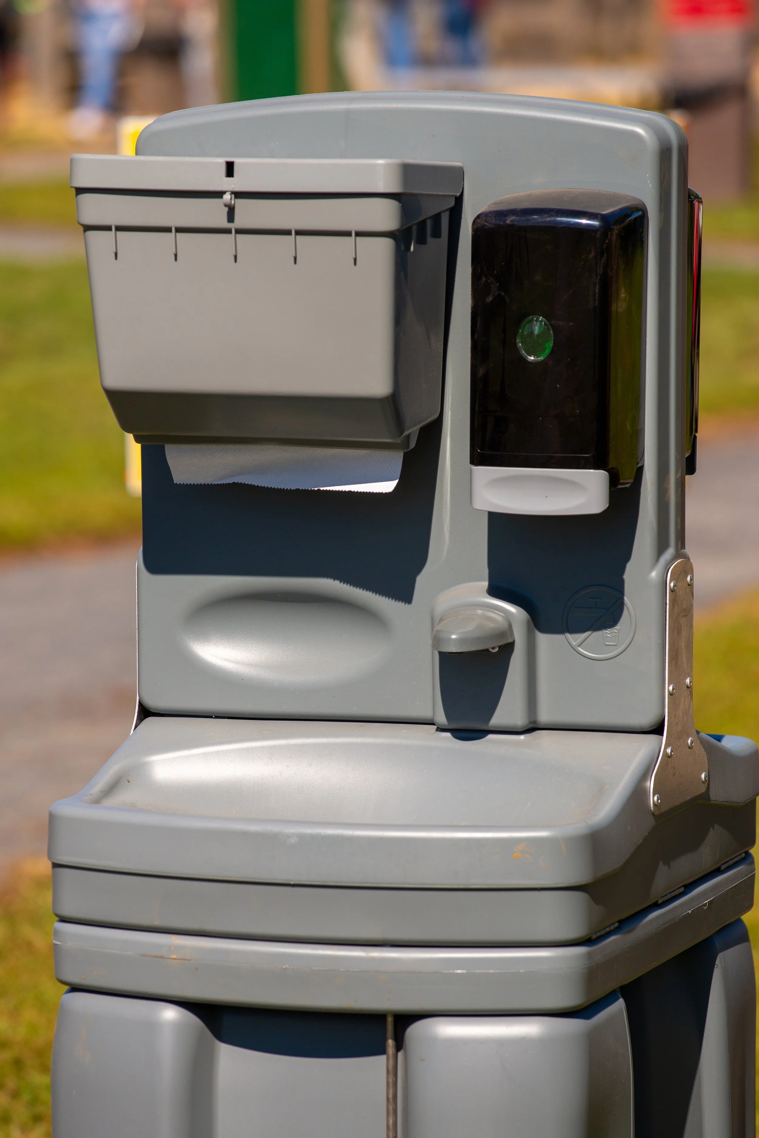 Rentable wash station with a gray and black design in an outdoor park setting.