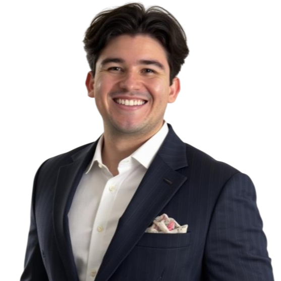 Black and white photo of a smiling man in a suit, with dark hair, wearing a white shirt and pocket square.
