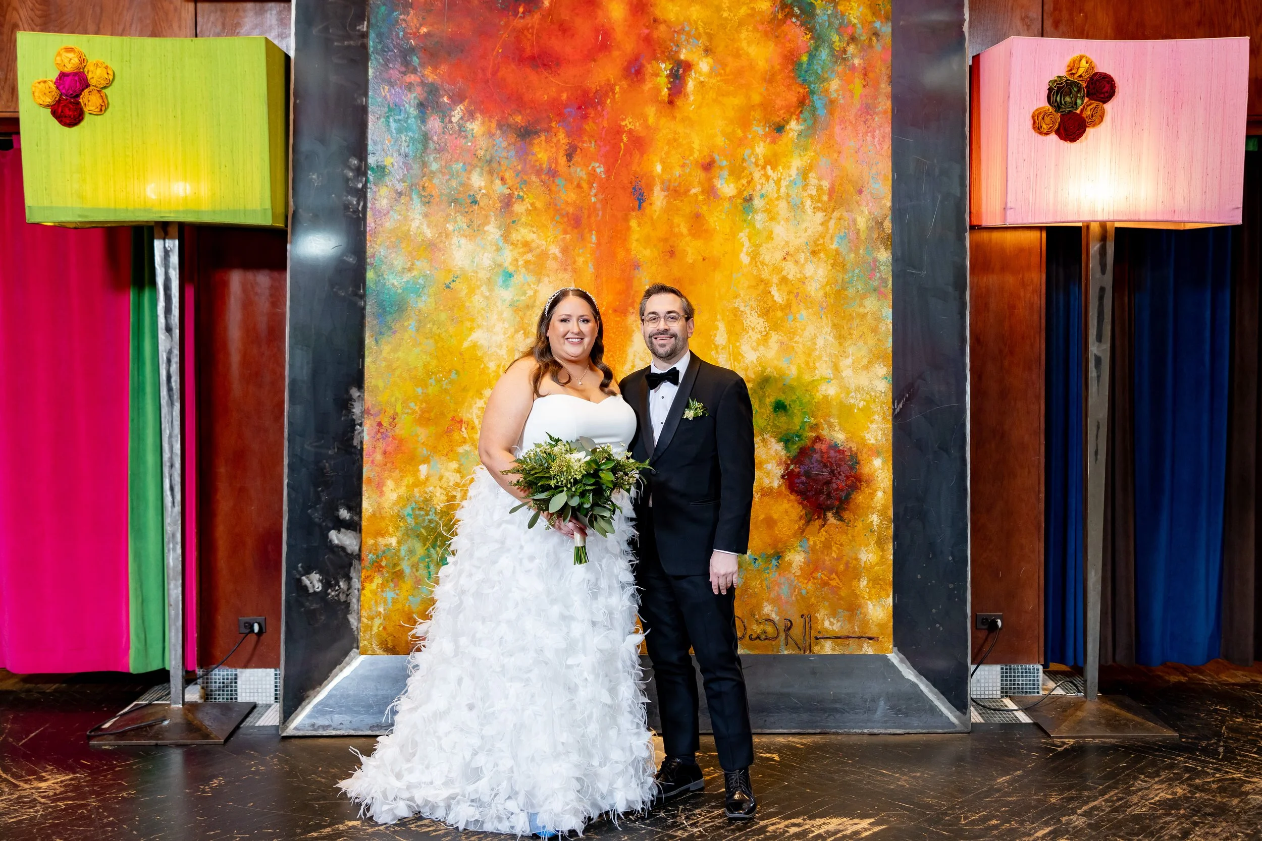 A happy bride and groom posing at Carnivale restaurant in Chicago during their colorful winter wedding ceremony and reception, coordinated by One Fine Day Events.