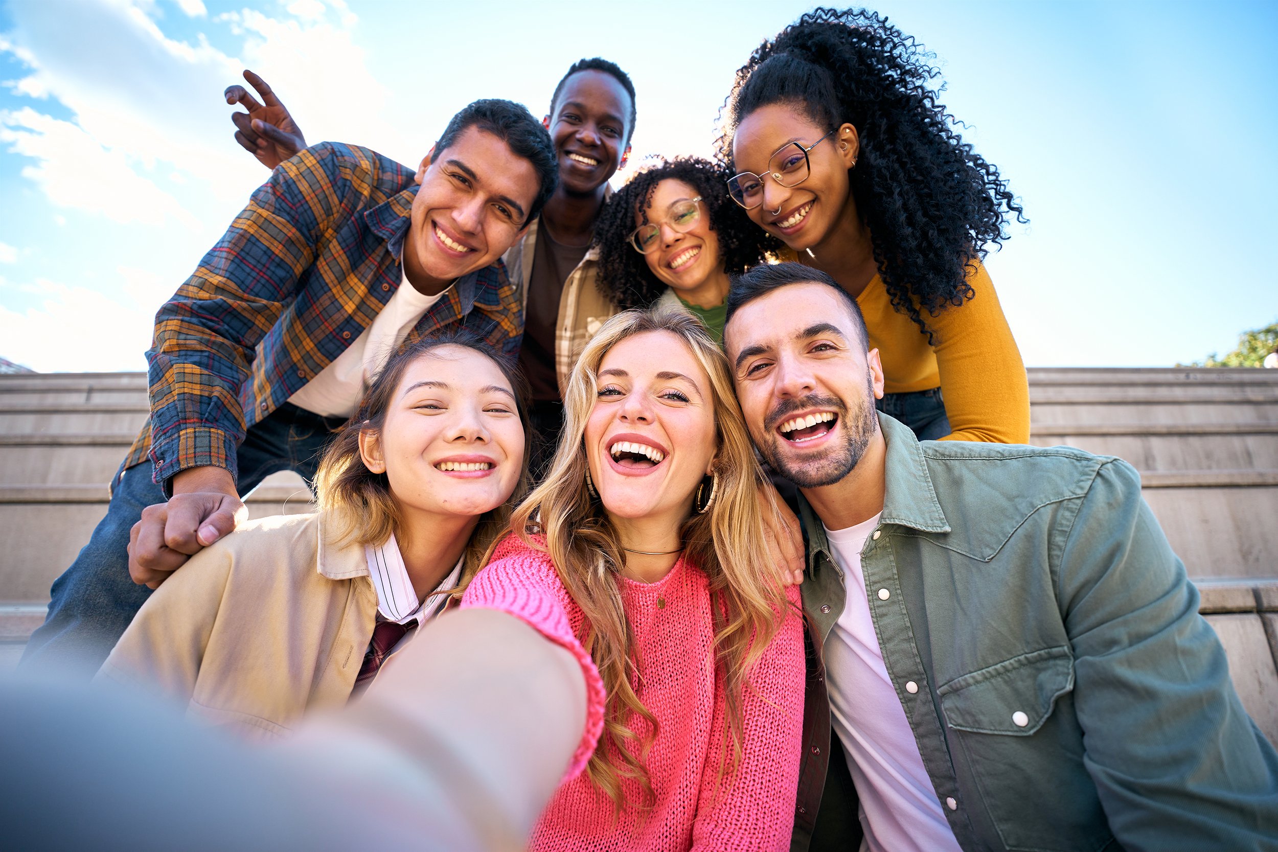 A group of ethnically diverse people smiling for a selfie.