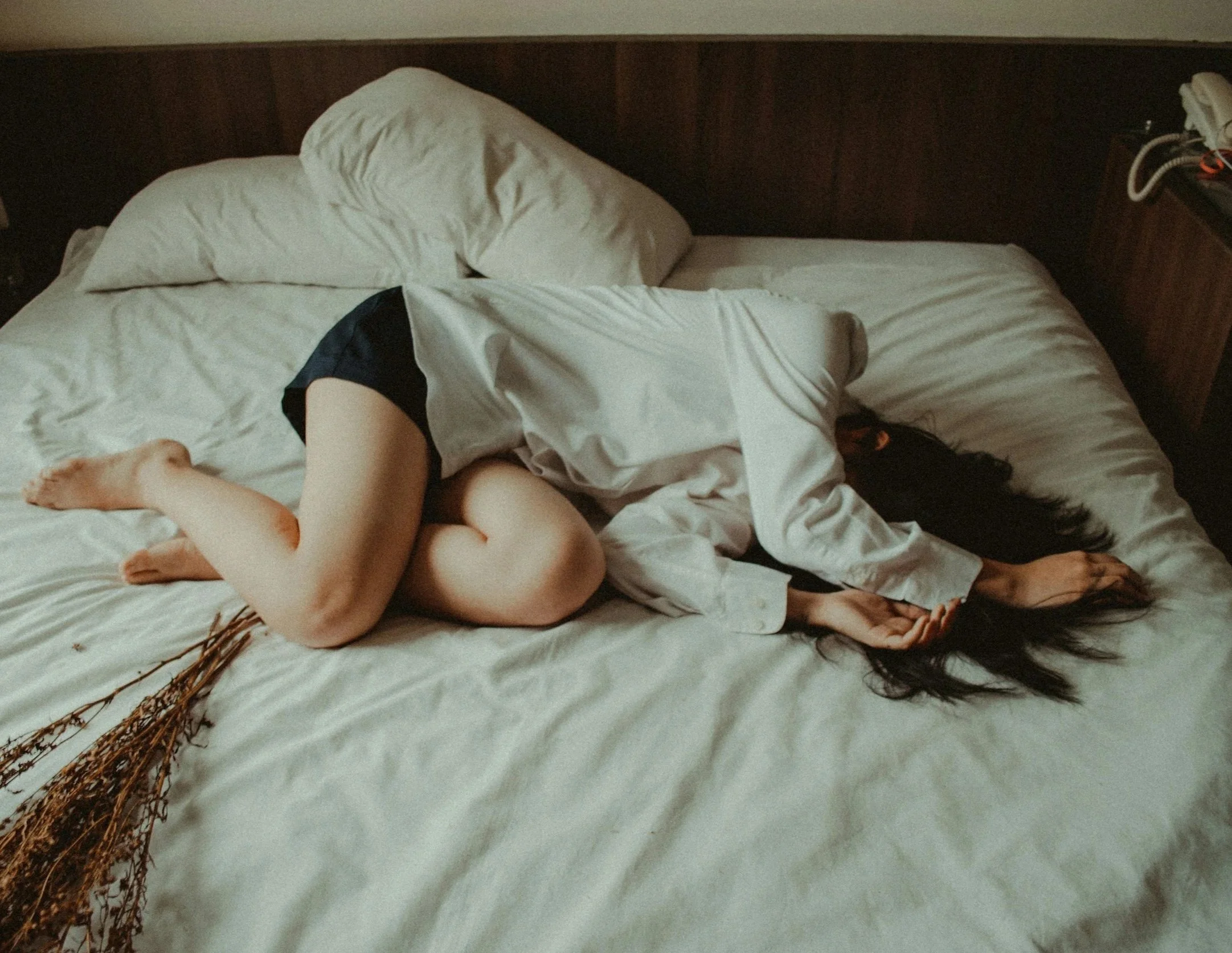 White woman laying on bed after sexual trauma therapy at Ash & Blooms.
