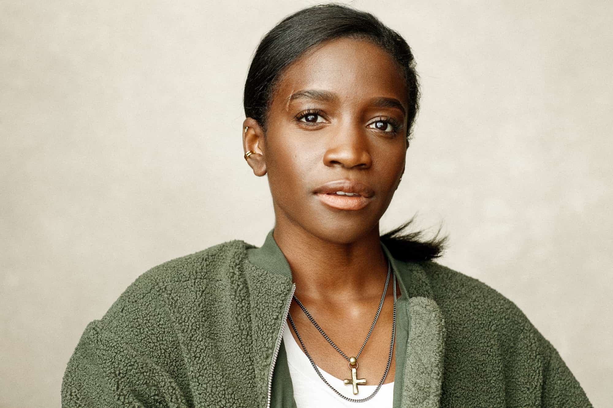 black actress headshot with Jewellery and a green fleece on soft background